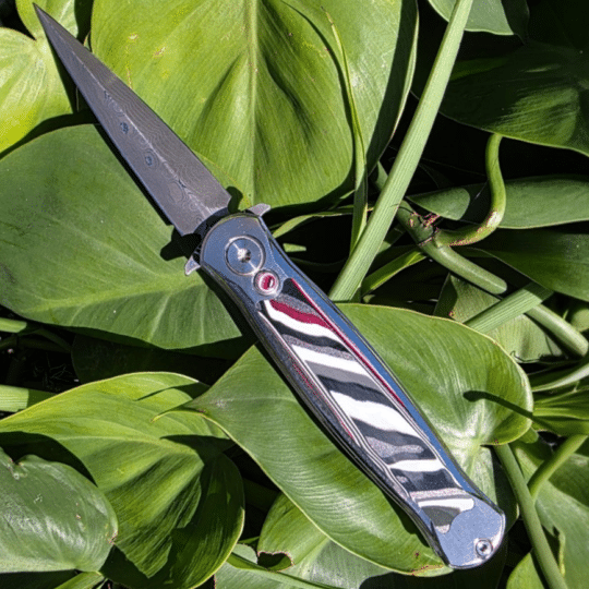 RMOR Knives Skunk custom folding dagger with Vegas Forge Typhoon 440C blade and striped Fordite inlays