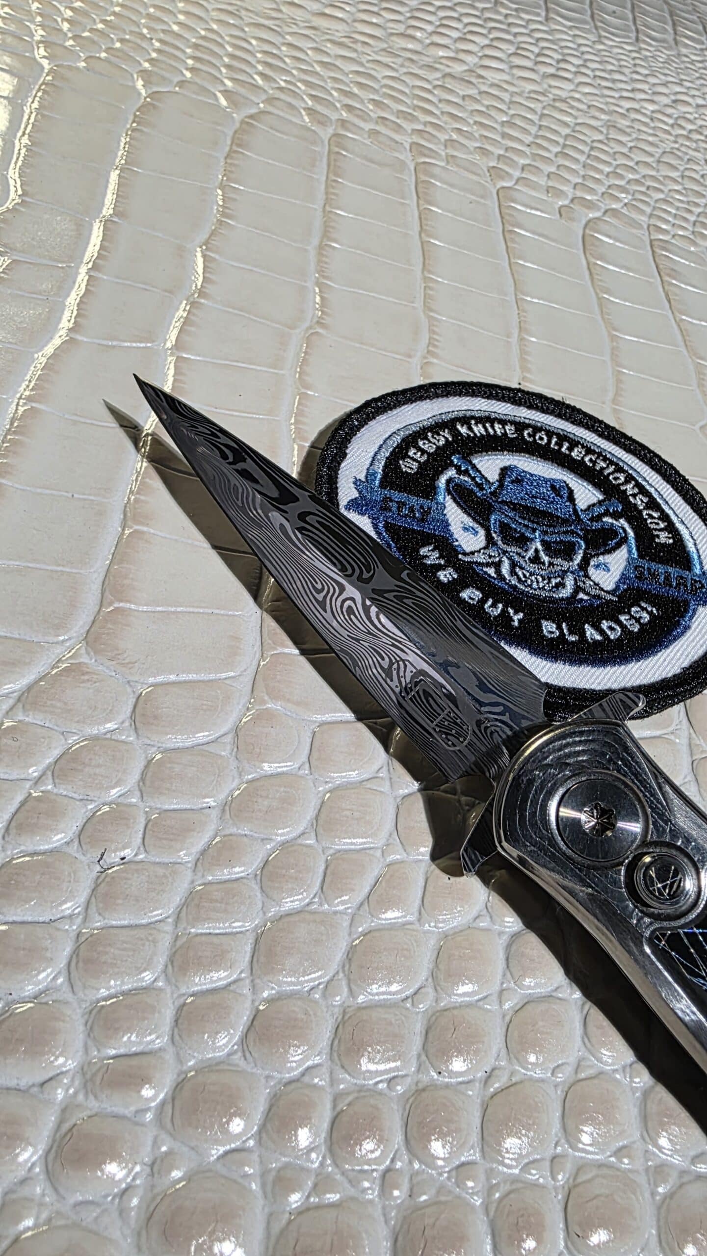 Detail view of RMOR Knives Skunk showing Loki pattern Damascus and polished titanium hardware