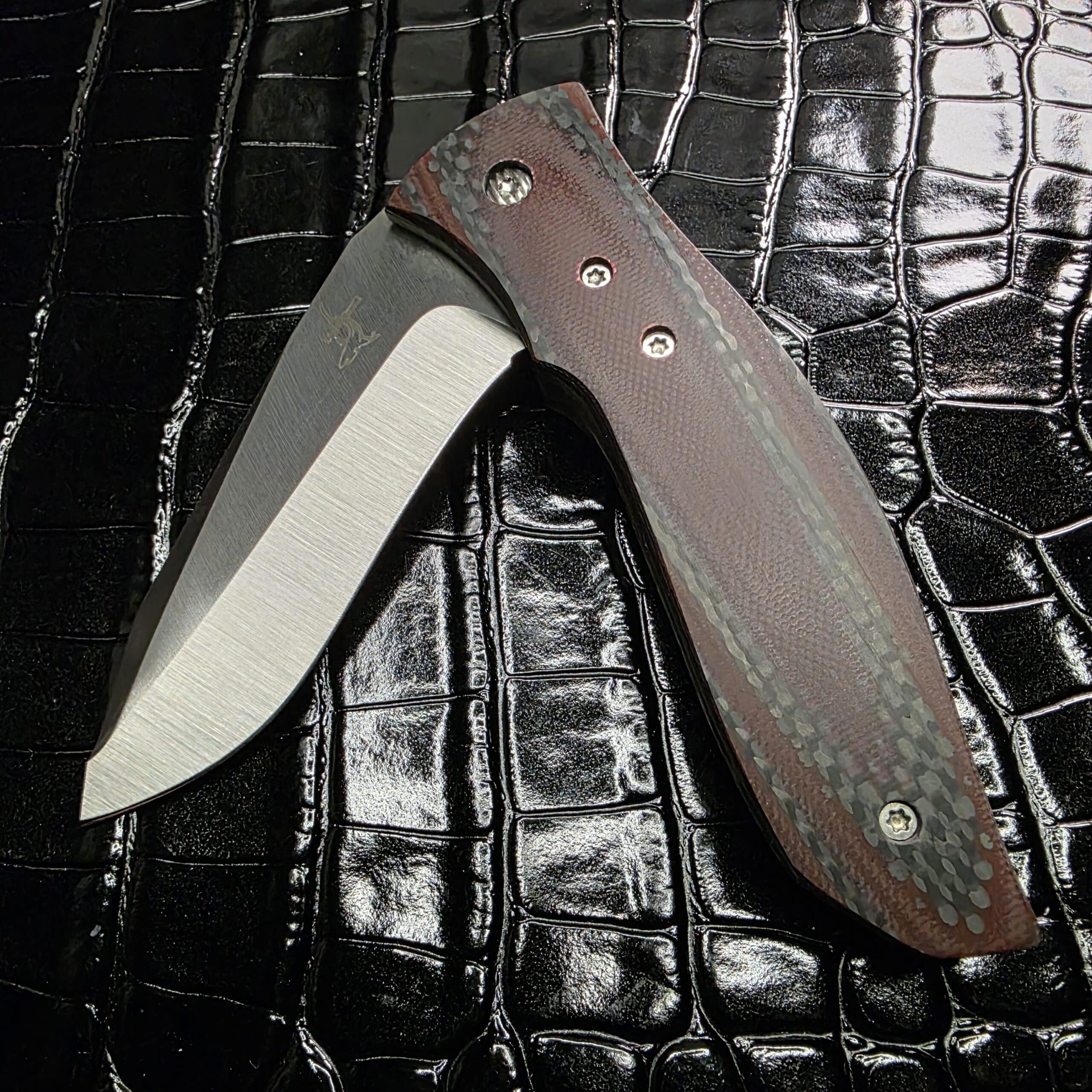 Close-up of red carbon fiber weave on a Greg Lightfoot knife handle.