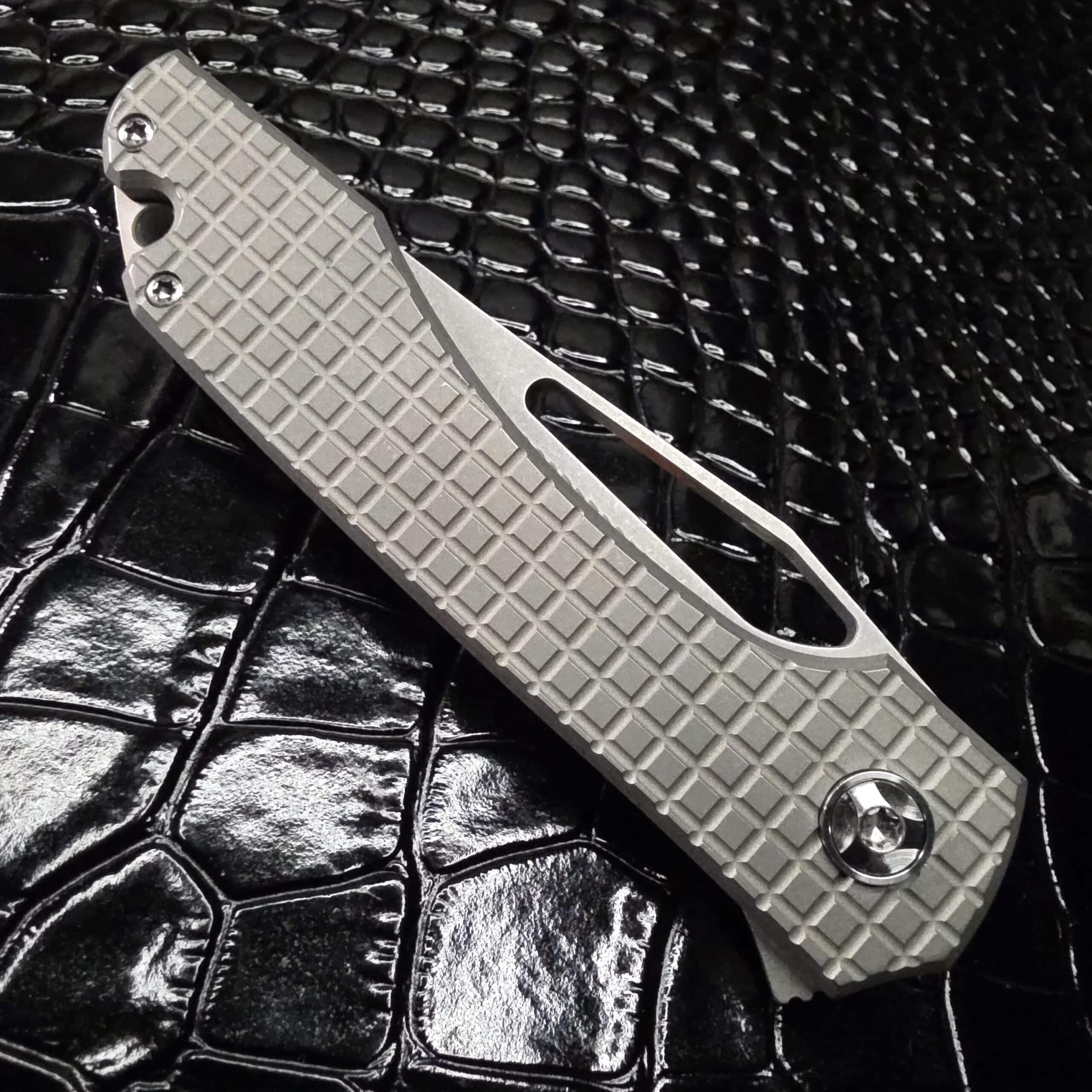 Close up of frag pattern titanium handle on Simeon UnTo showing tumbled texture and grip