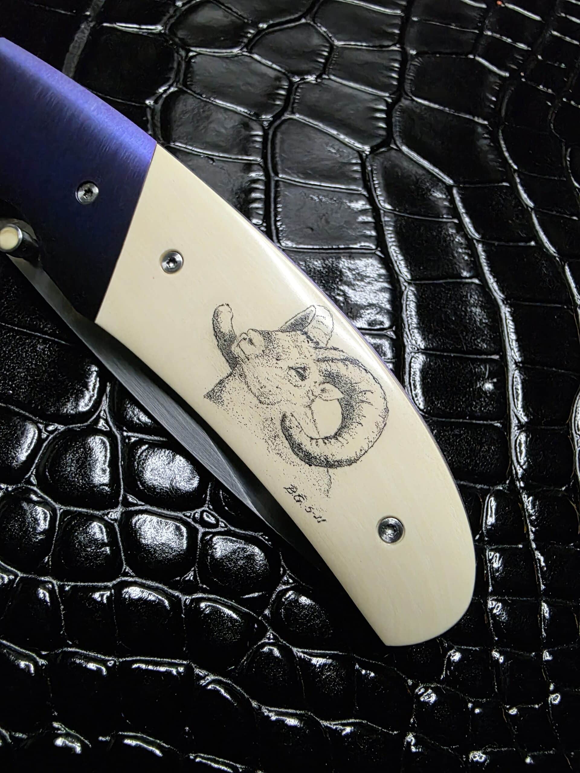 Detailed hand-scrimshaw of a bighorn ram on mammoth ivory handle scales of a Buddy Gaines custom knife.