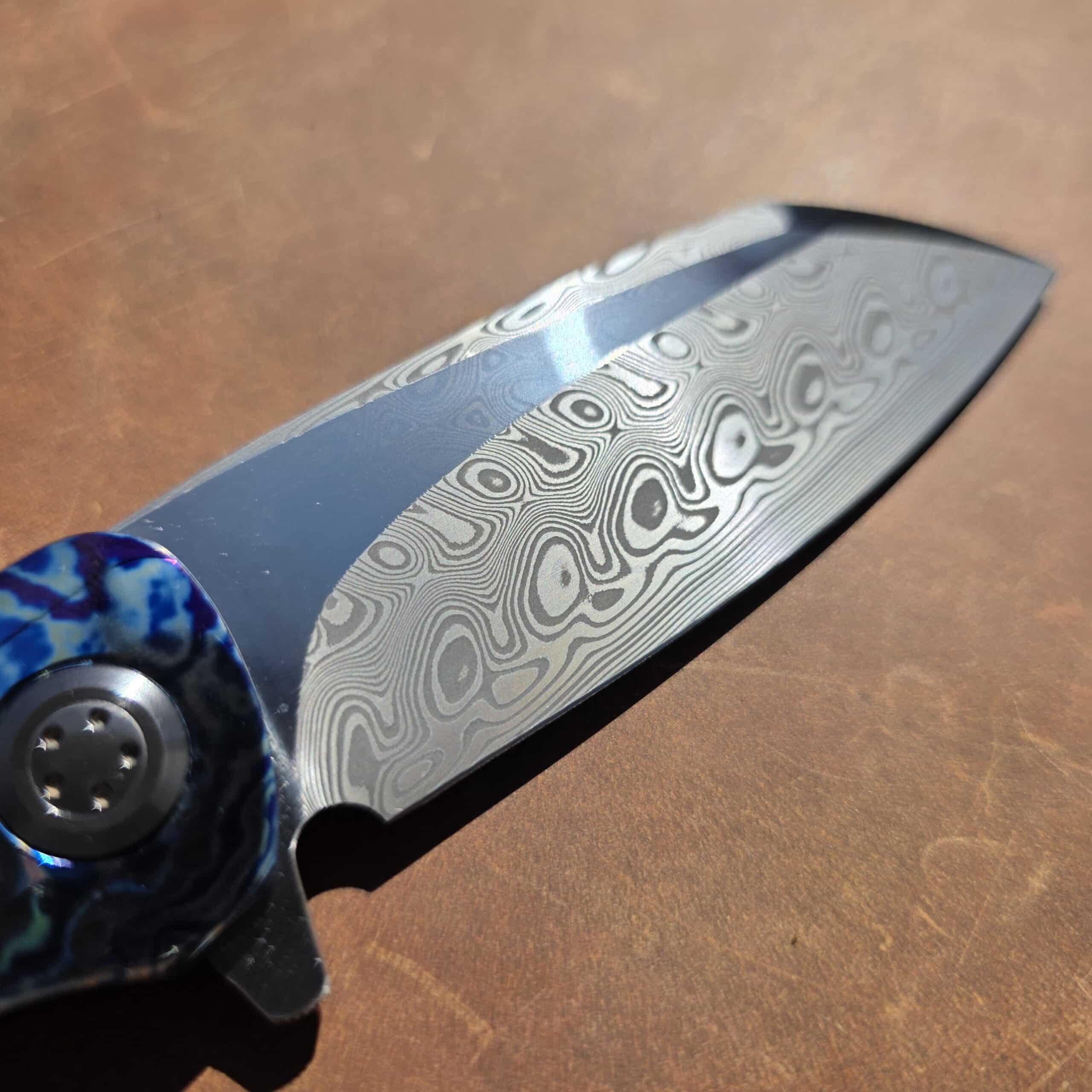 Extreme macro close-up of the high-contrast pattern-welded Damasteel Sweden steel on a Herucus Blomerus custom blade.