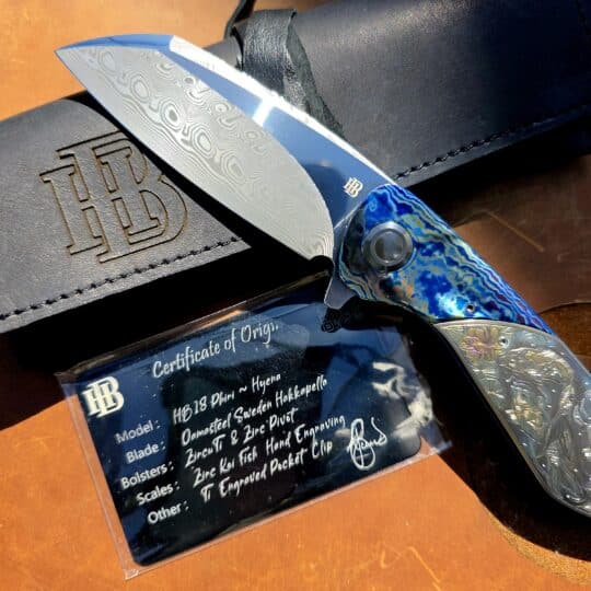 Herucus Blomerus HB18 Phiri Hyena custom knife featuring intricate hand-engraving by Ilze du Plessis and Zircuti bolsters.