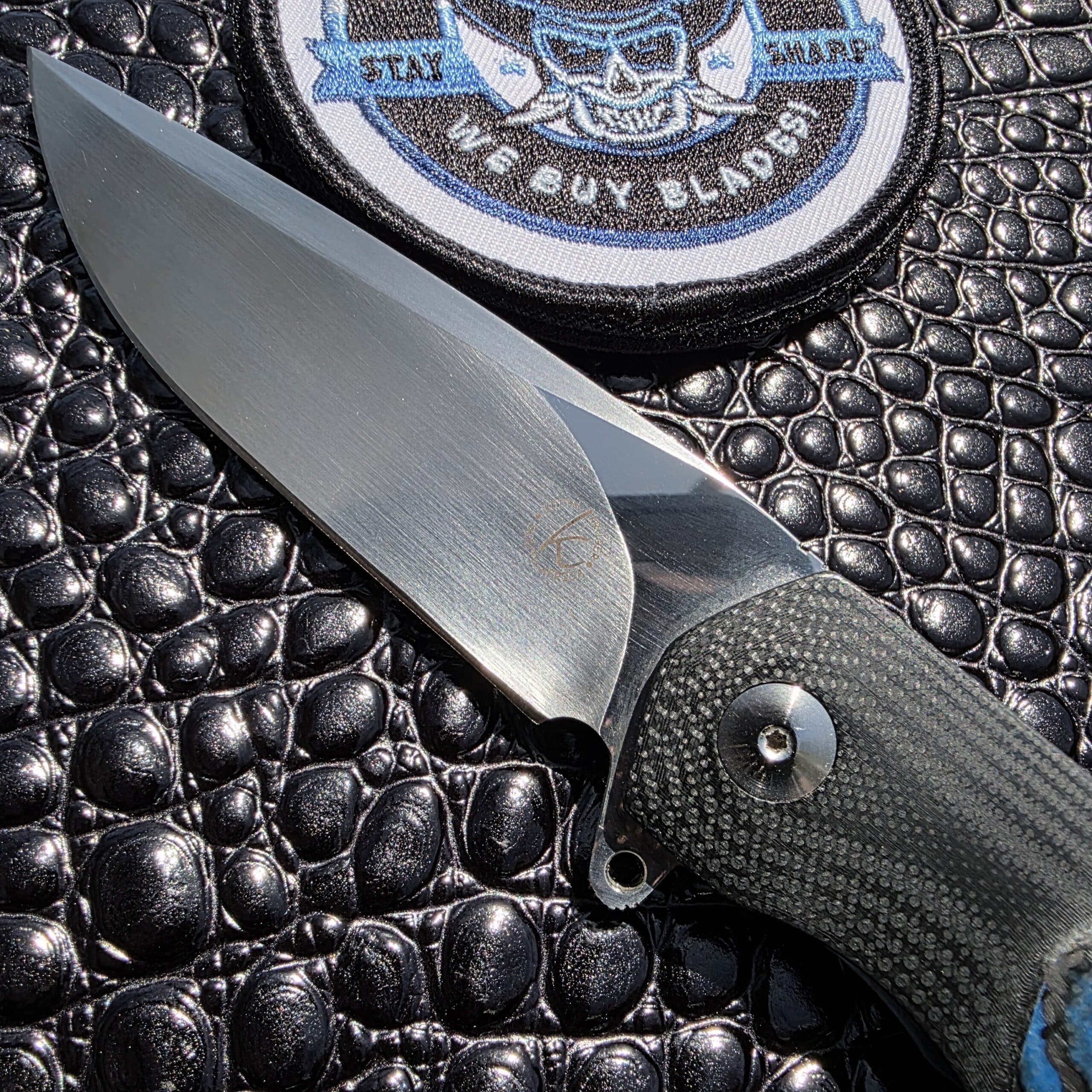 Macro view of the hand-hollow ground satin blade on a Keith Kruger Custom K4.