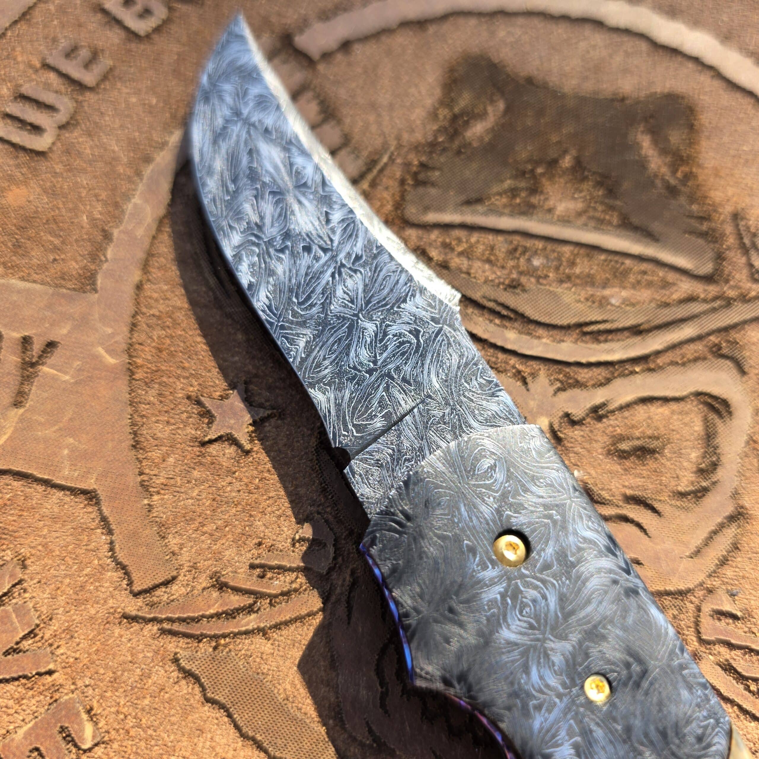Deep flowing mosaic Damascus on the blade and bolsters of a Scott Gallagher knife.