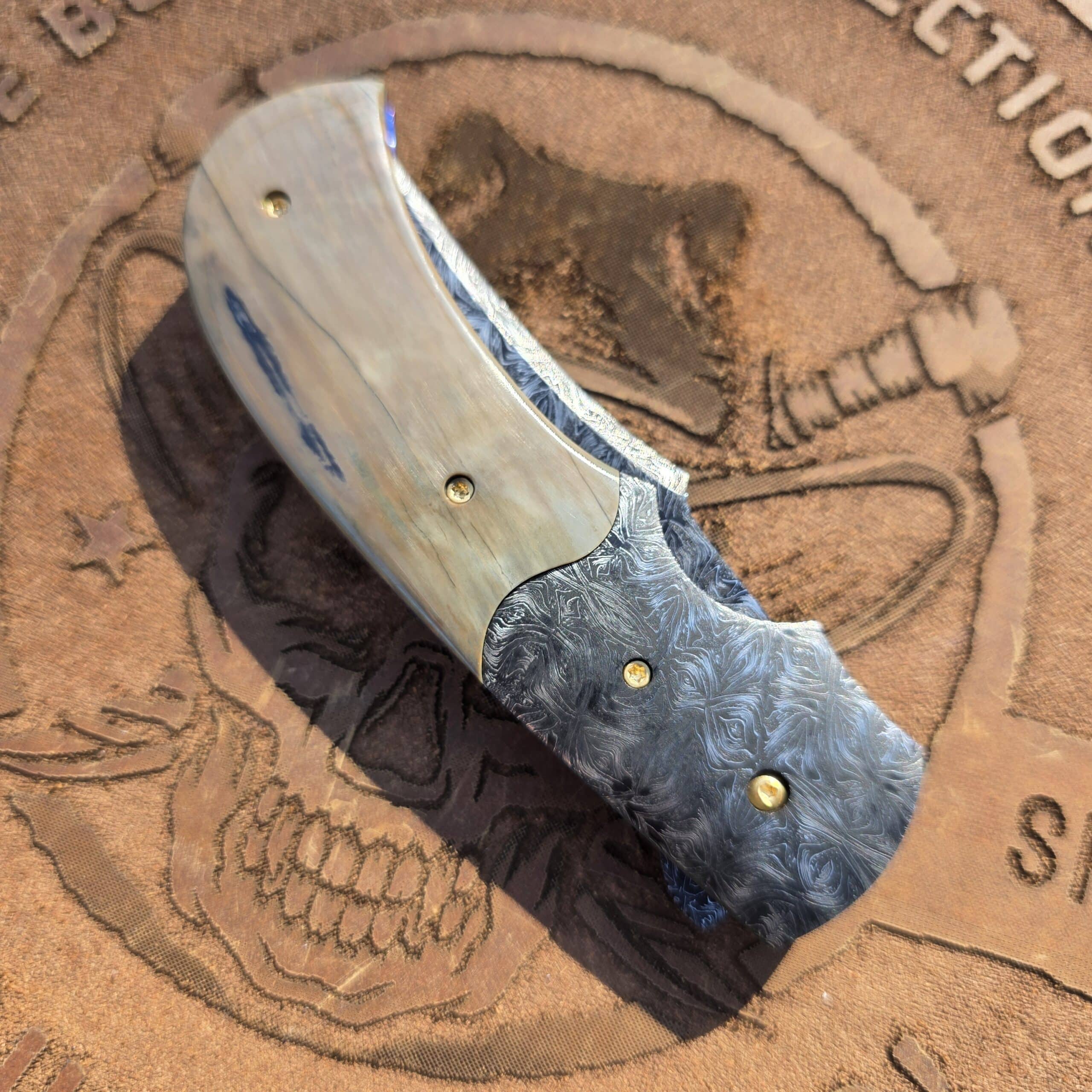 Close-up of natural mammoth ivory handle scales on a custom folder.