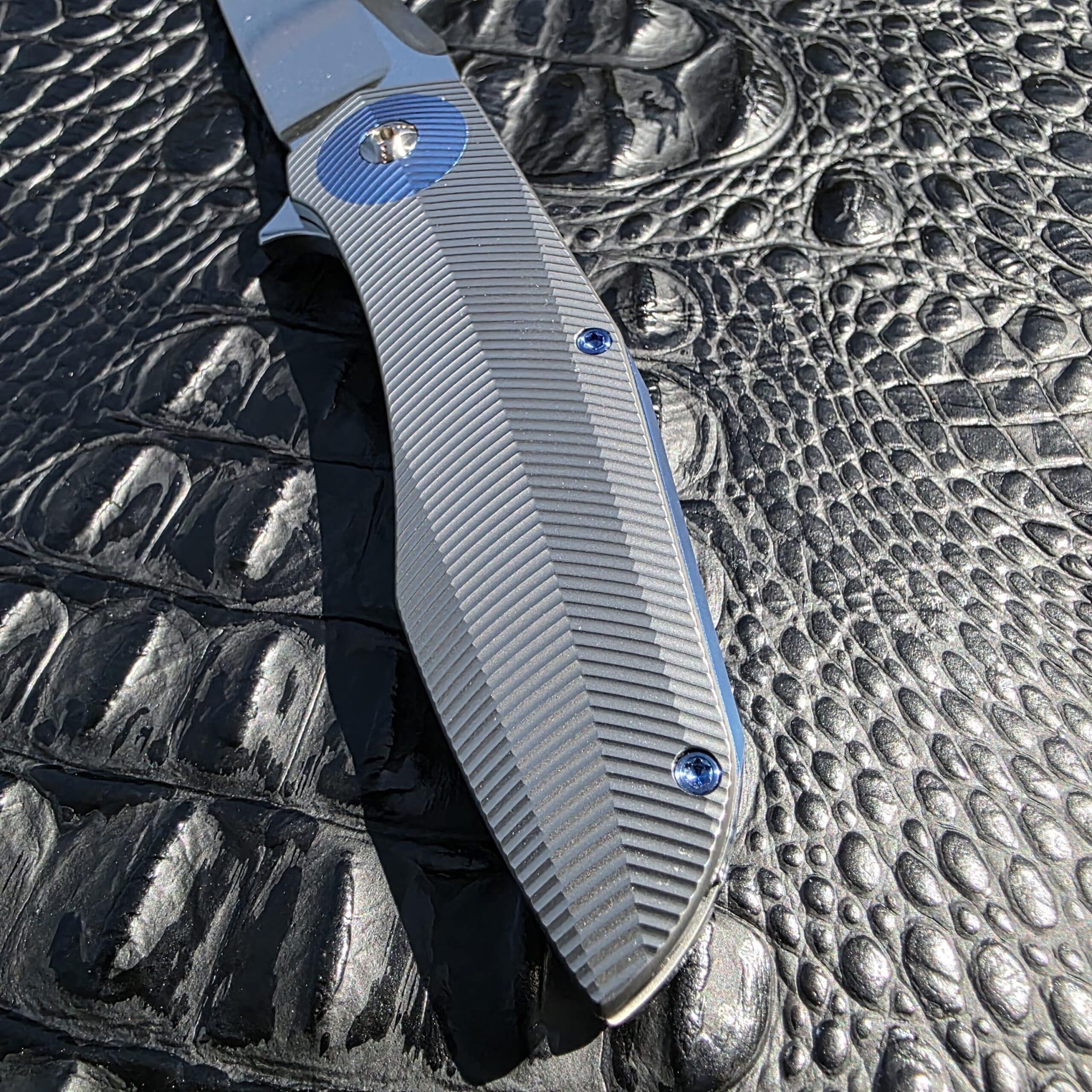 Blade-side titanium handle detail on Skiff Made Blades Culprit with herringbone milling