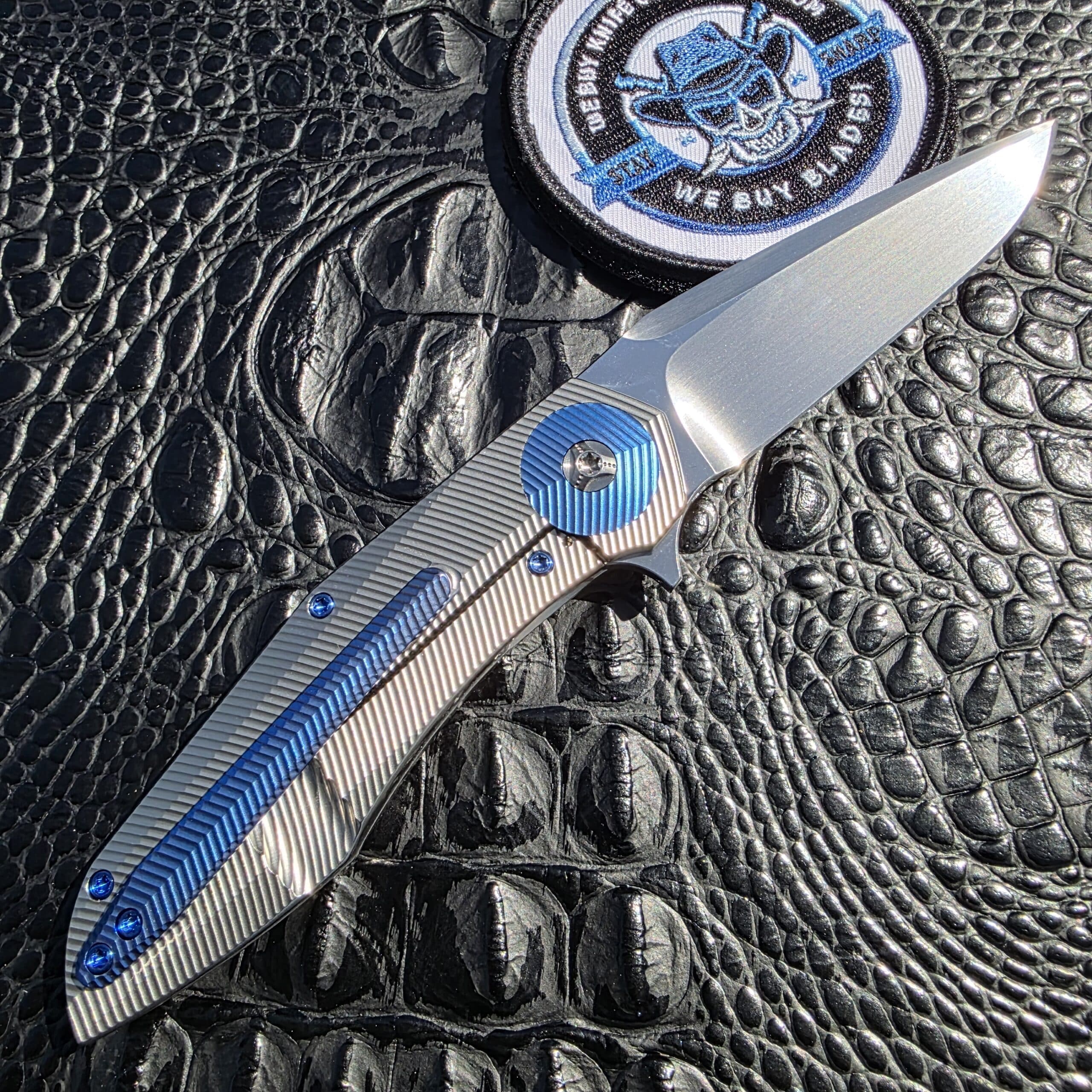 Open clip-side view of Skiff Made Blades Culprit with blue anodized titanium clip