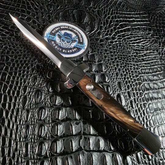 Burn Knives Italian stiletto double action OTF deployed on black crocodile leather with buffalo horn scales and mirror-polished 154CM dagger blade