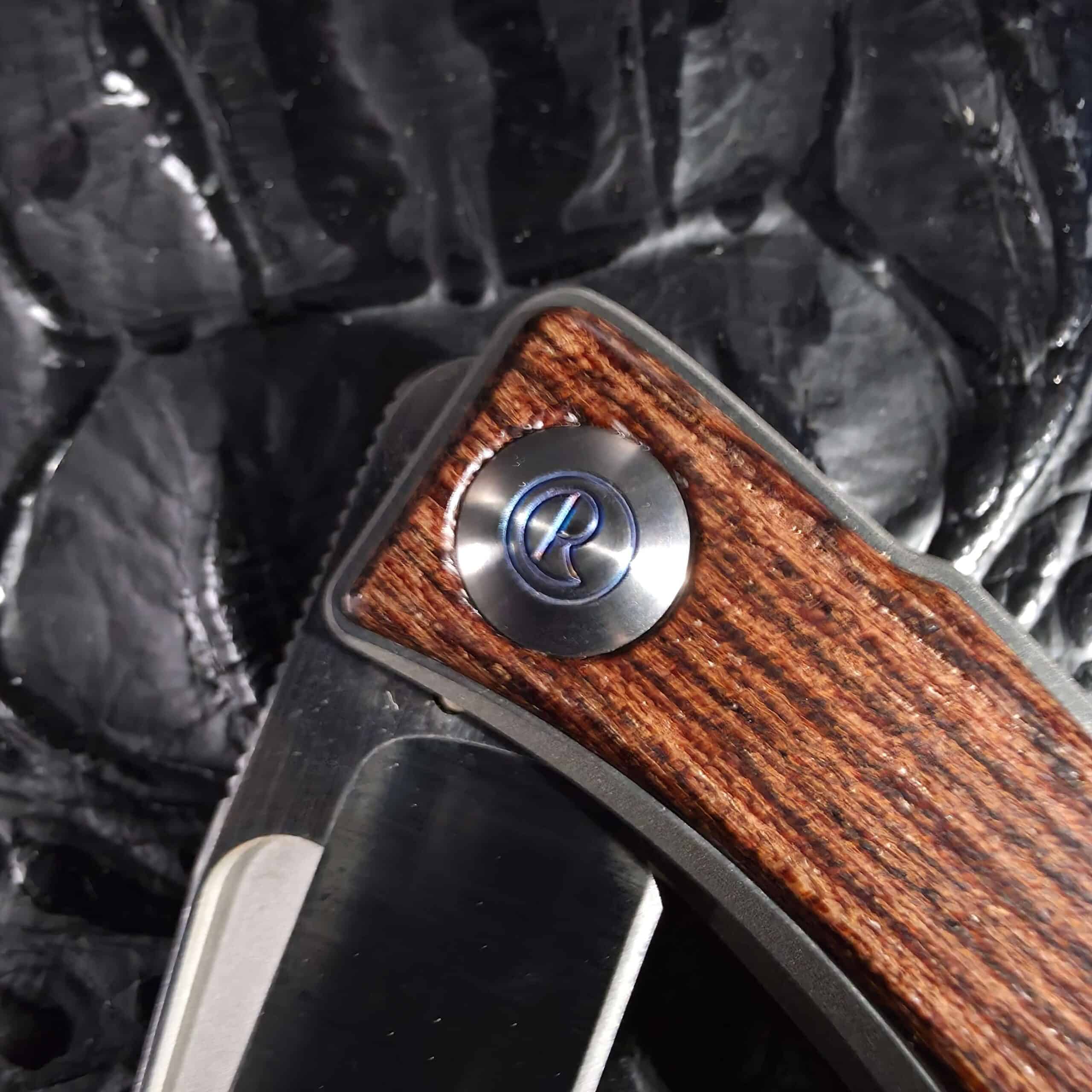 Blue anodized Chris Reeve R pivot cap set into Bocote wood inlay