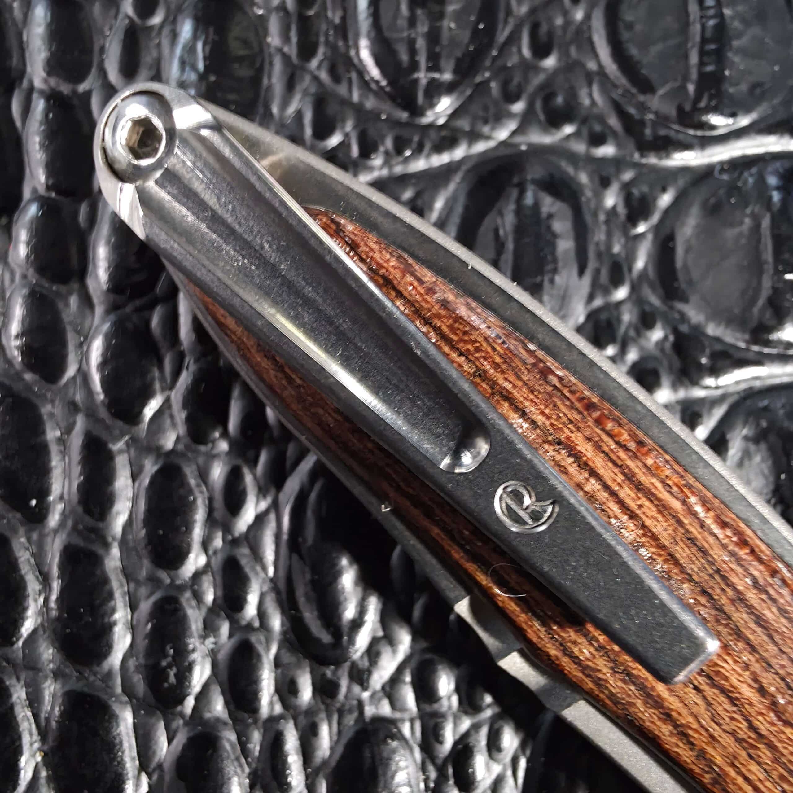 Machined titanium pocket clip with exposed top screw and Chris Reeve logo