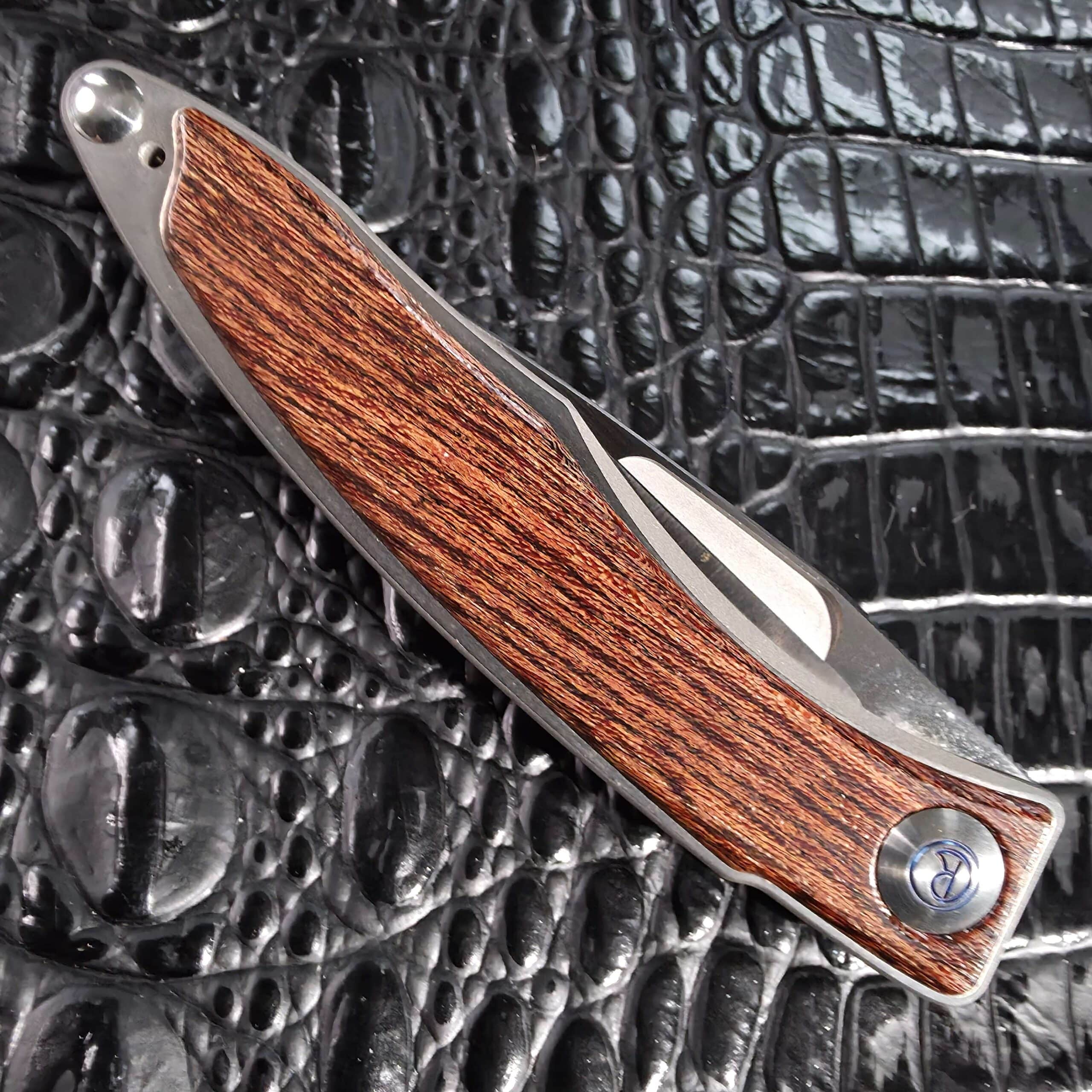 Closed show side of the Chris Reeve Mnandi Bocote with blue anodized R pivot cap