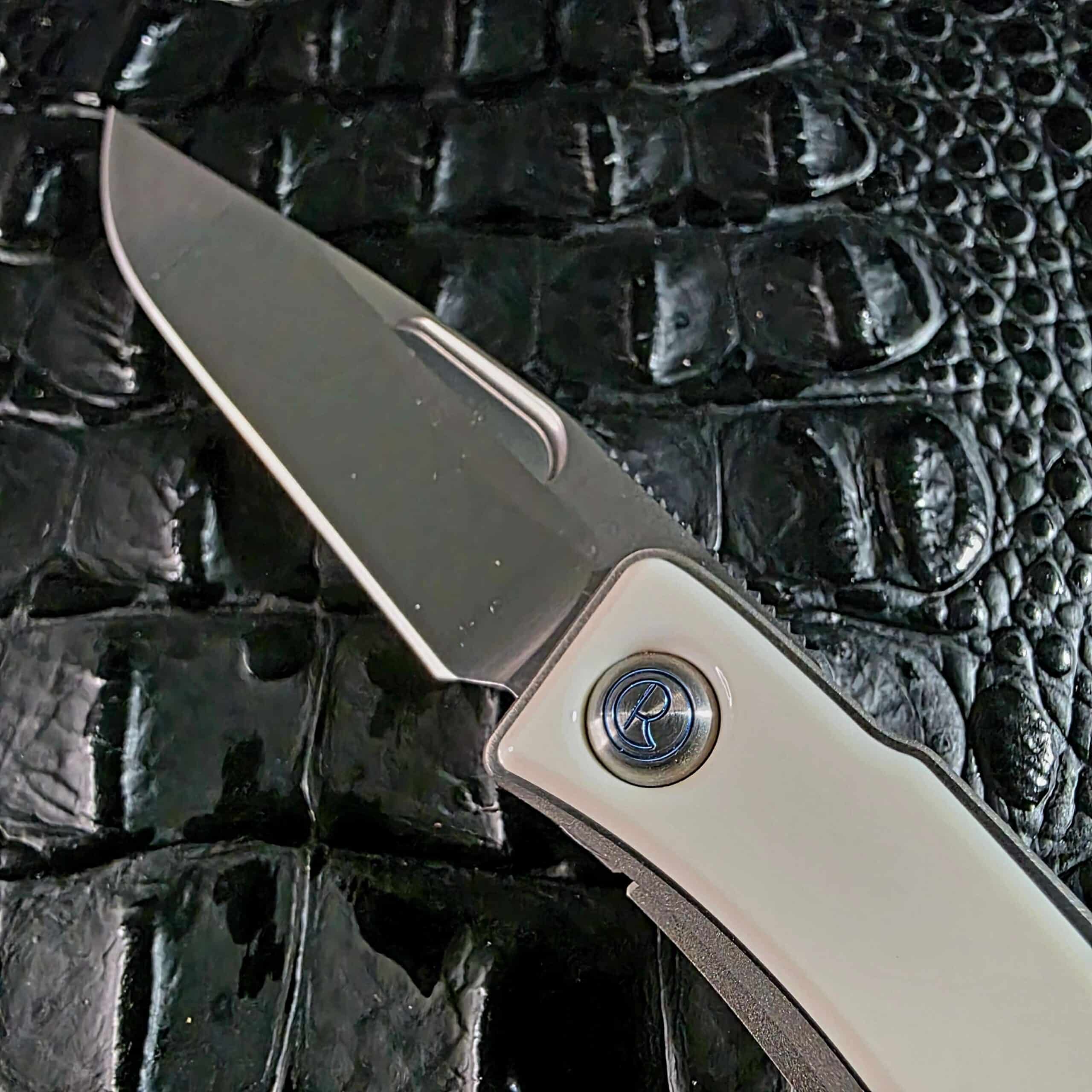 Blue-anodized Chris Reeve logo pivot medallion set into the mammoth ivory inlay beside the S35VN blade