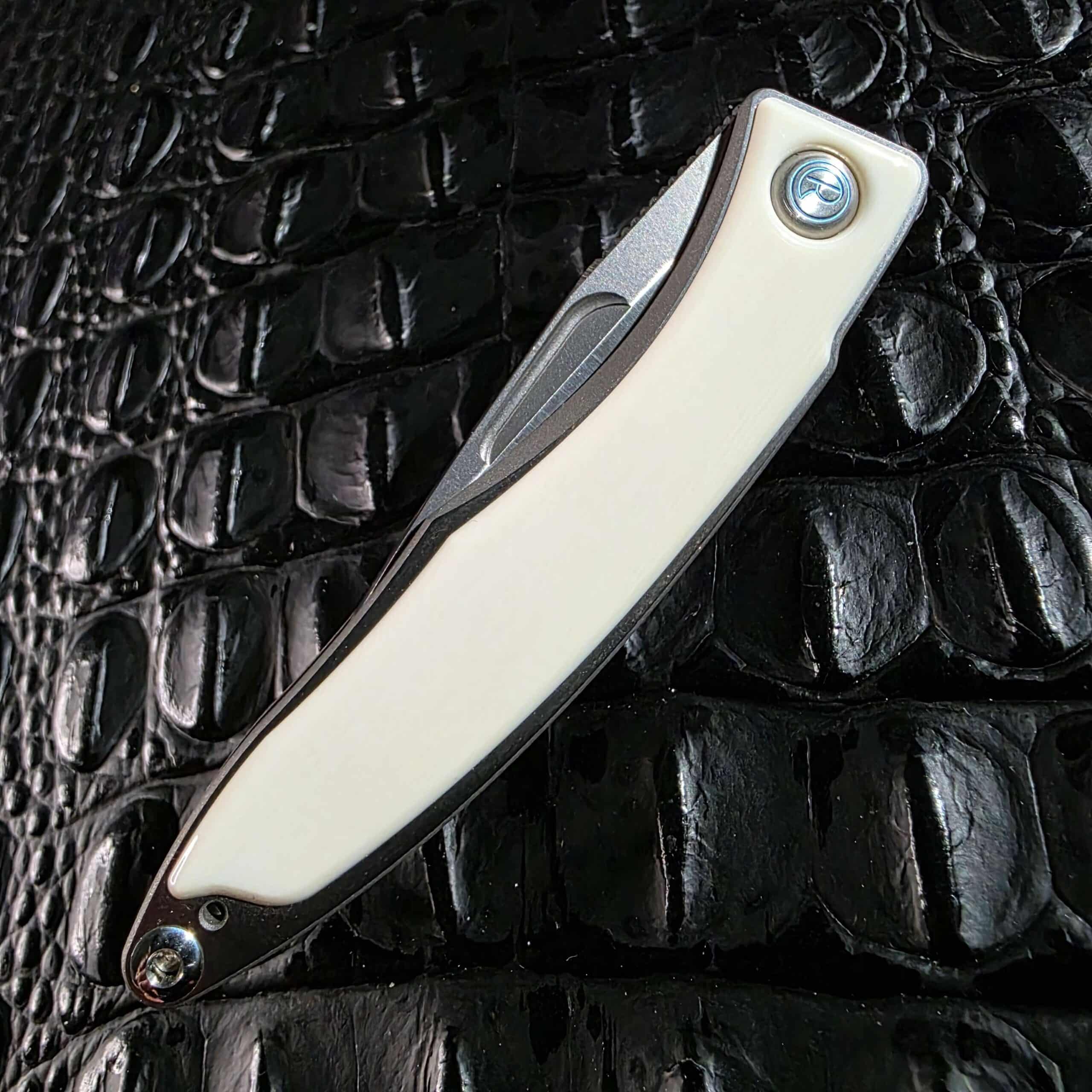 Closed show side of the Chris Reeve Mnandi displaying the full white mammoth ivory inlay and blue pivot medallion