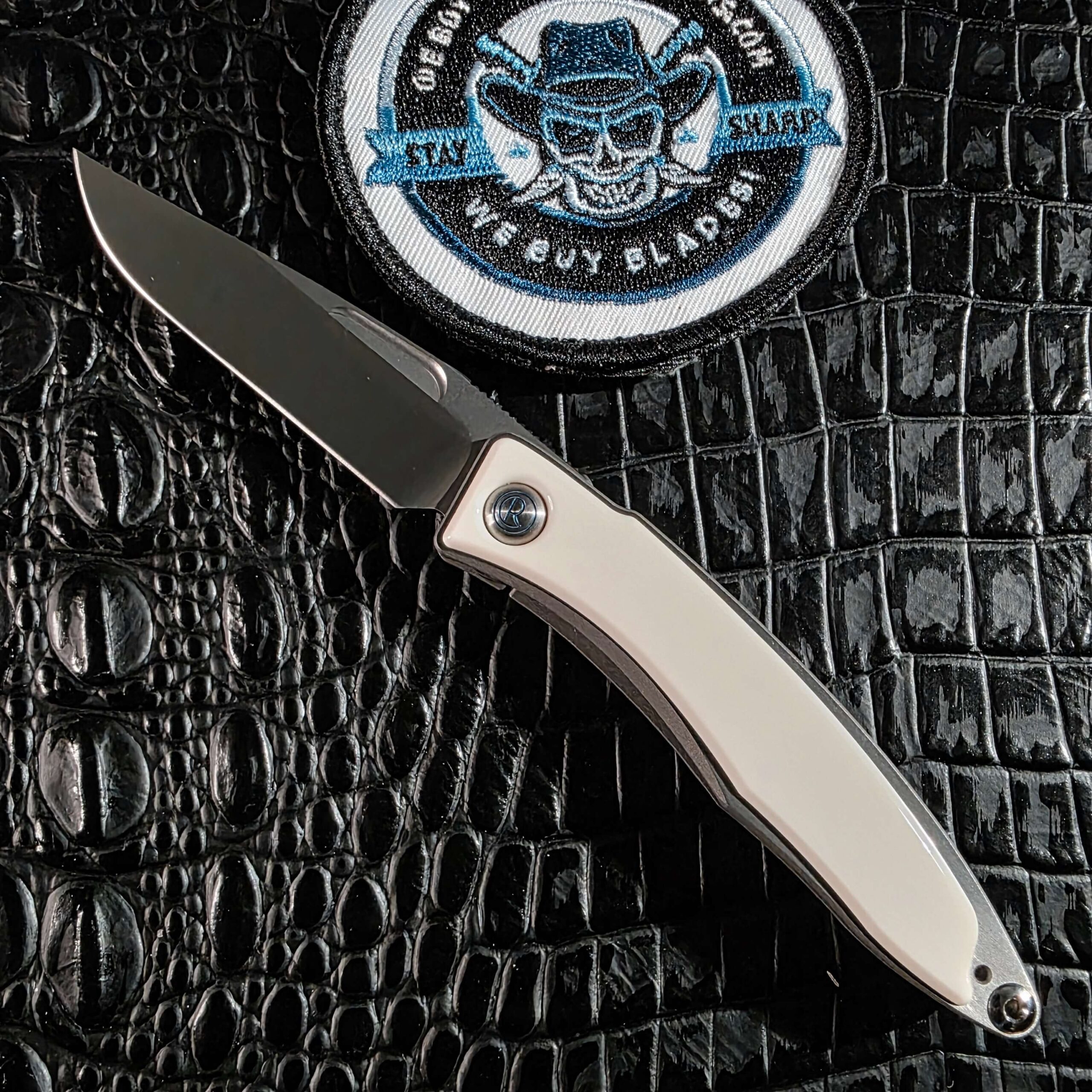 Chris Reeve Mnandi open on black crocodile leather with white mammoth ivory inlays and hand-rubbed CPM S35VN blade