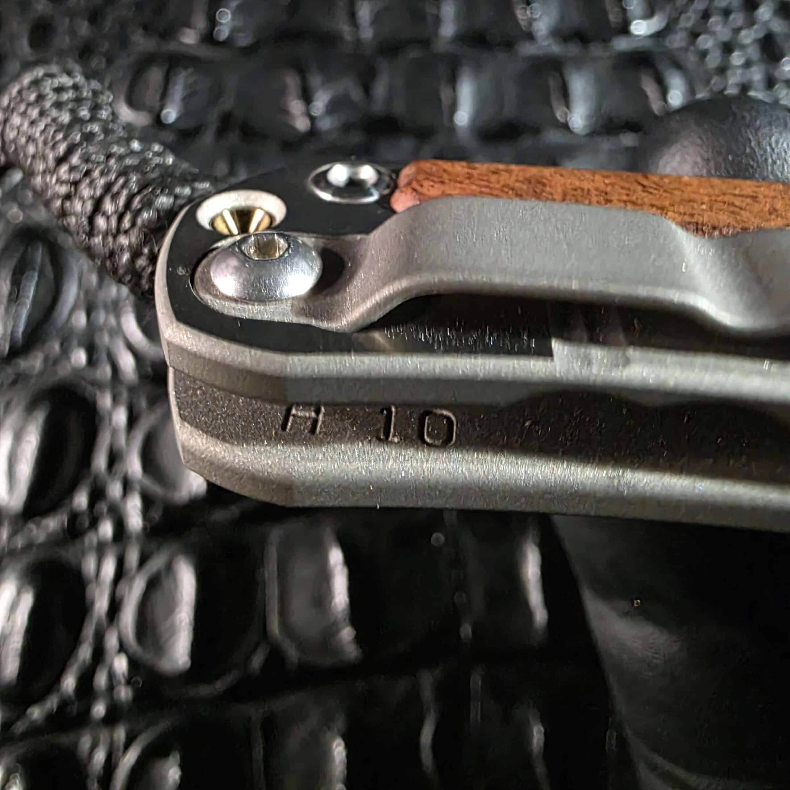 Butt end of the Chris Reeve Small Sebenza 2010 Annual showing a stamped marking, gold-anodized screw, and titanium slabs