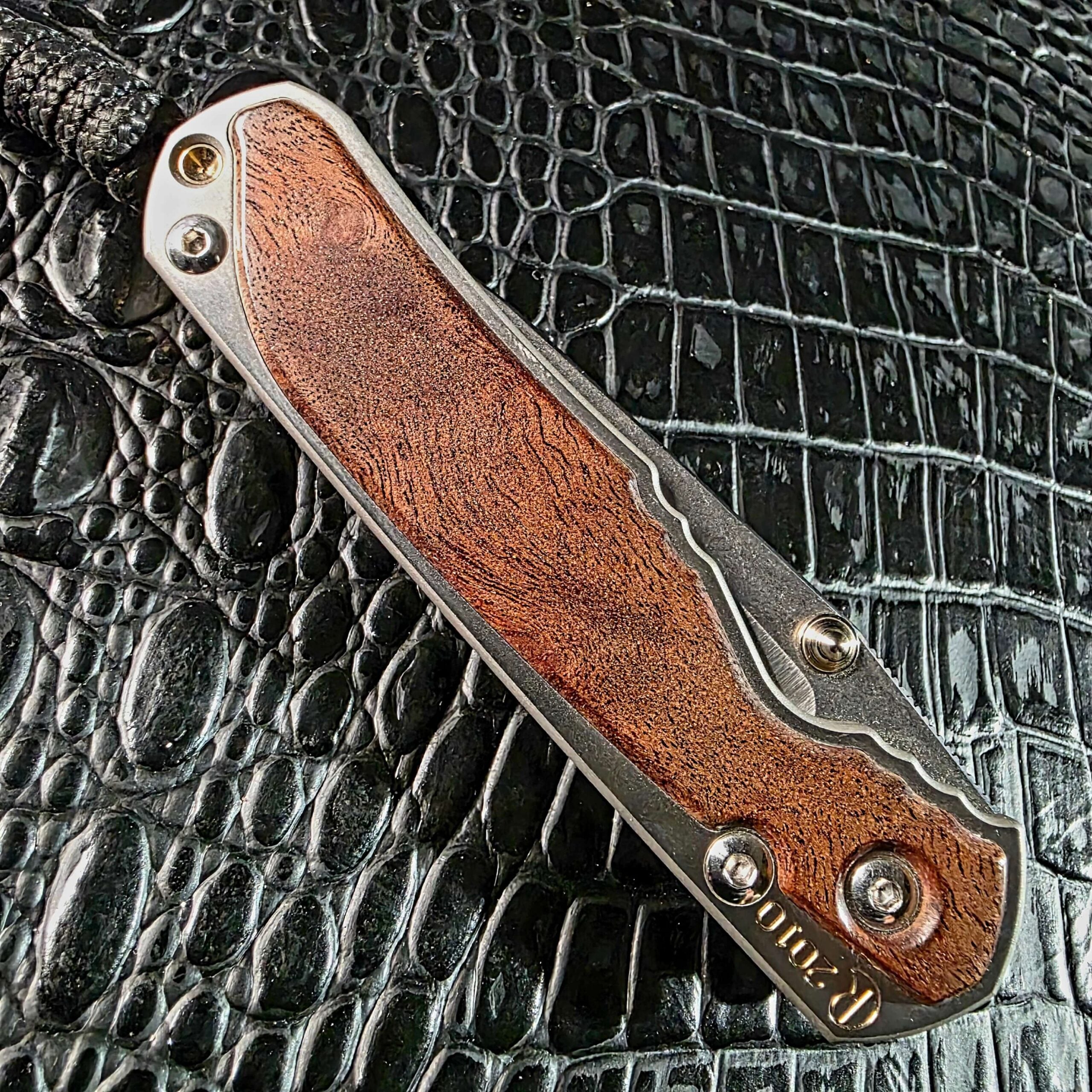 Closed Chris Reeve Small Sebenza 2010 Annual showing the full camphor burl show-side inlay and R 2010 year engraving