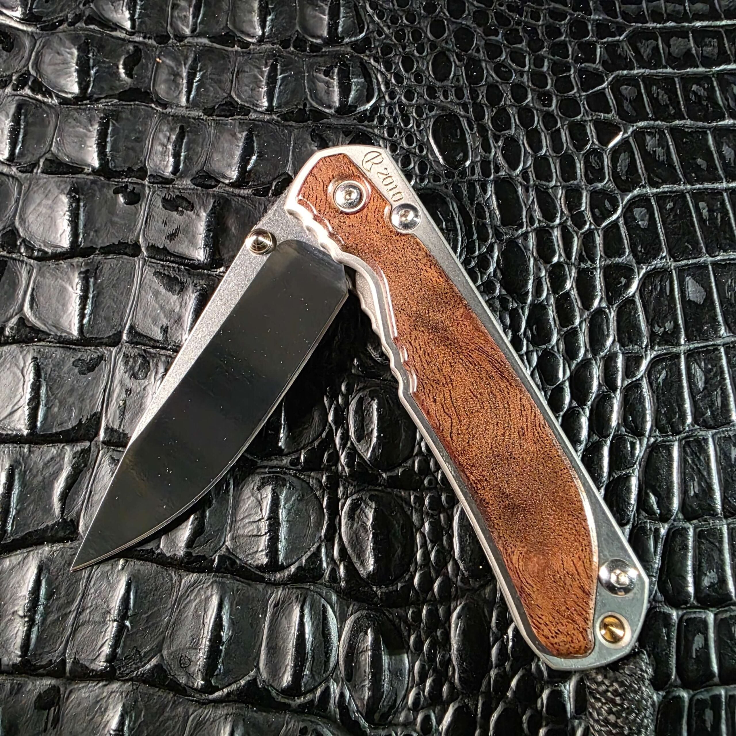 Chris Reeve Small Sebenza 2010 Annual shown half open, revealing the S30V blade against the camphor burl show-side inlay