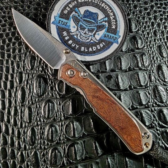 Chris Reeve Small Sebenza 2010 Annual Limited Edition open on black crocodile leather with camphor burl inlay and CPM-S30V drop point blade