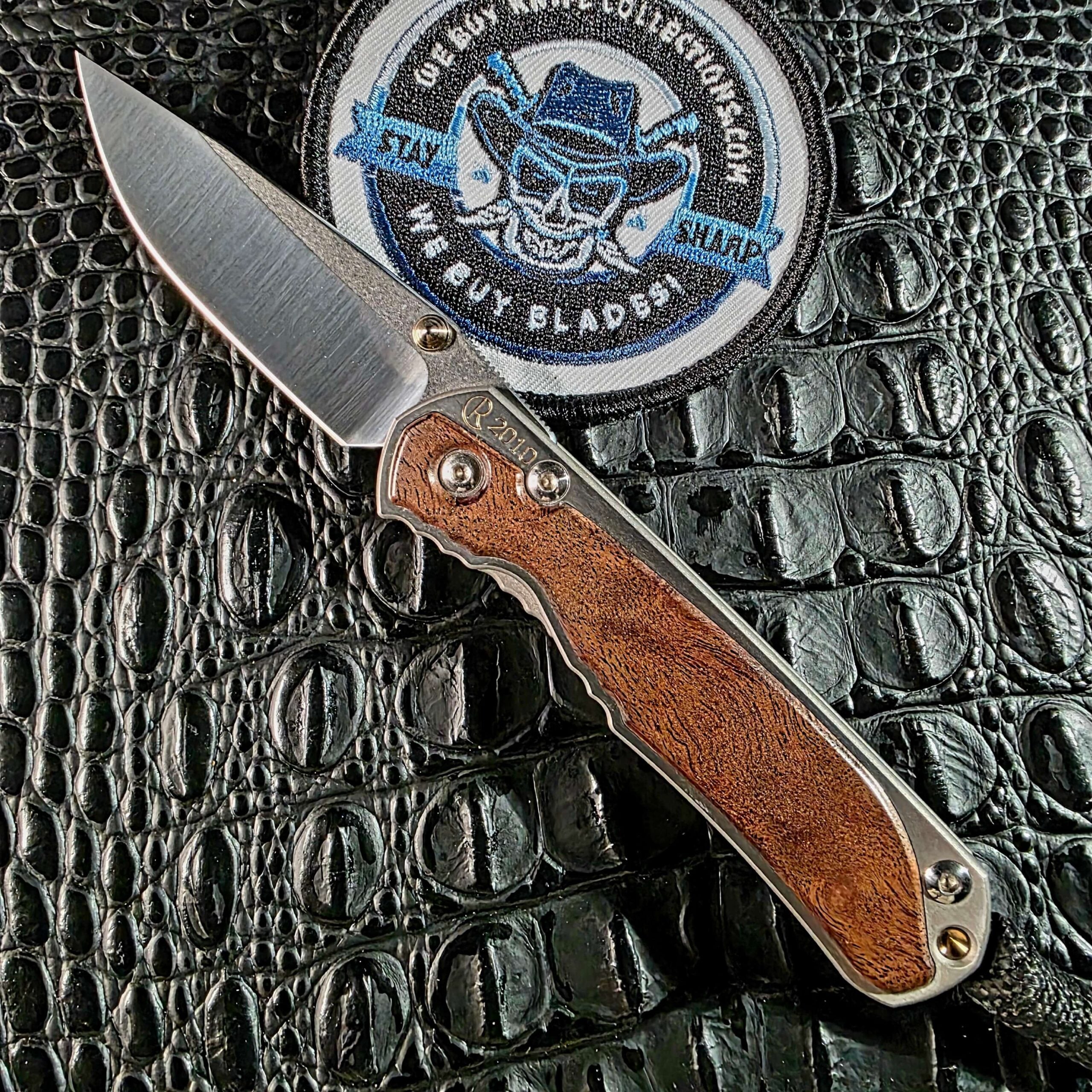 Chris Reeve Small Sebenza 2010 Annual Limited Edition open on black crocodile leather with camphor burl inlay and CPM-S30V drop point blade