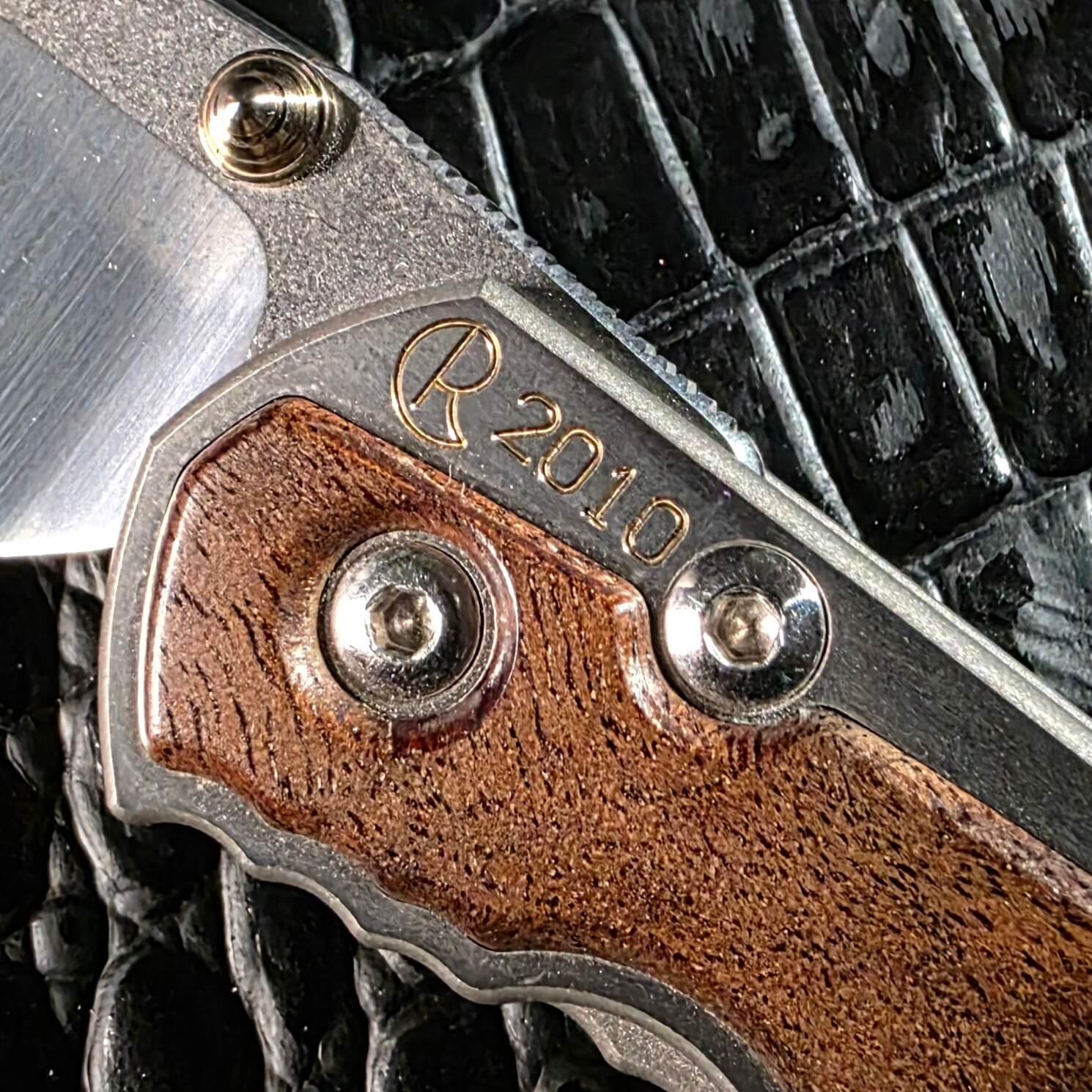 R 2010 year engraving on the titanium frame of the Chris Reeve Small Sebenza 2010 Annual Limited Edition beside the camphor burl inlay
