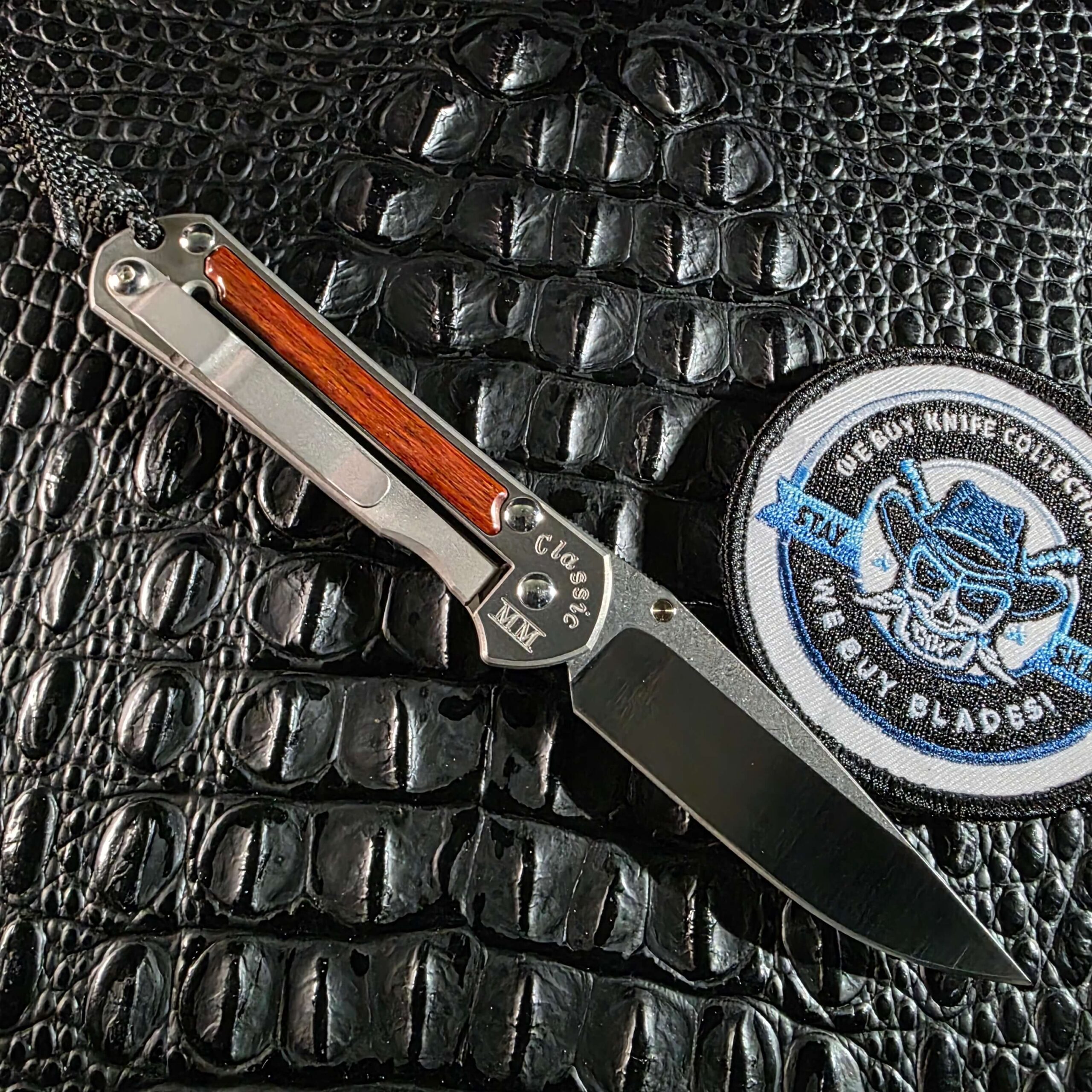 Chris Reeve Small Sebenza Classic MM lock side open beside We Buy Knife Collections patch
