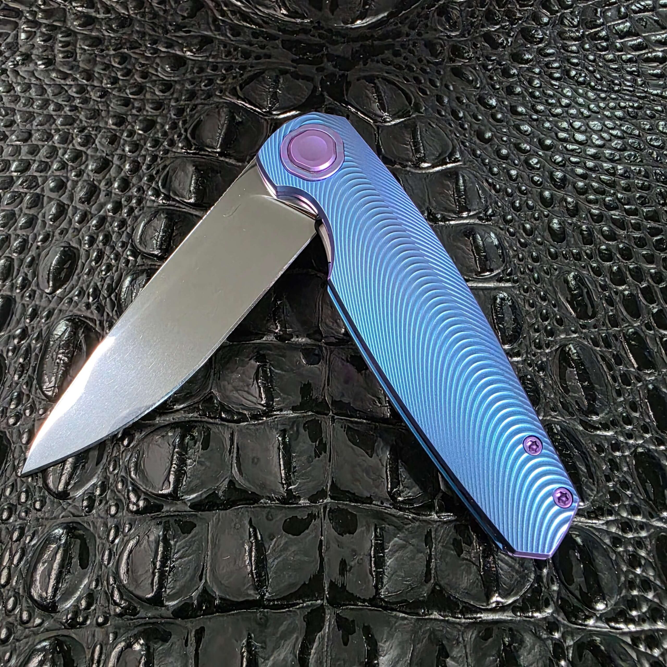 Angled open view of the Holt Bladeworks Morpheus #1856 showing the Triad-milled blue titanium scale and purple pivot