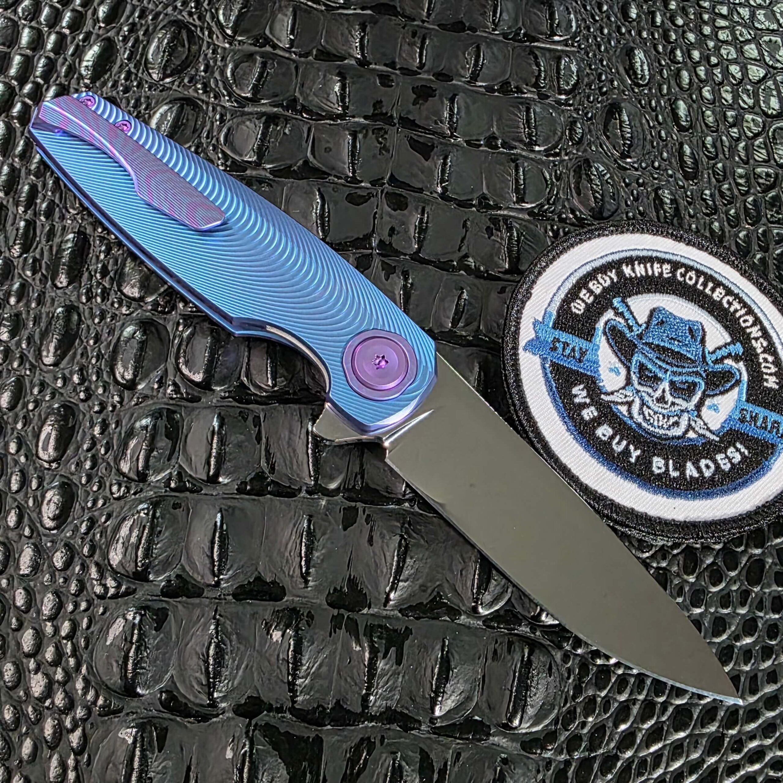 Clip side of the open Holt Bladeworks Morpheus #1856 showing the 25V anodized titanium pocket clip and purple pivot collar