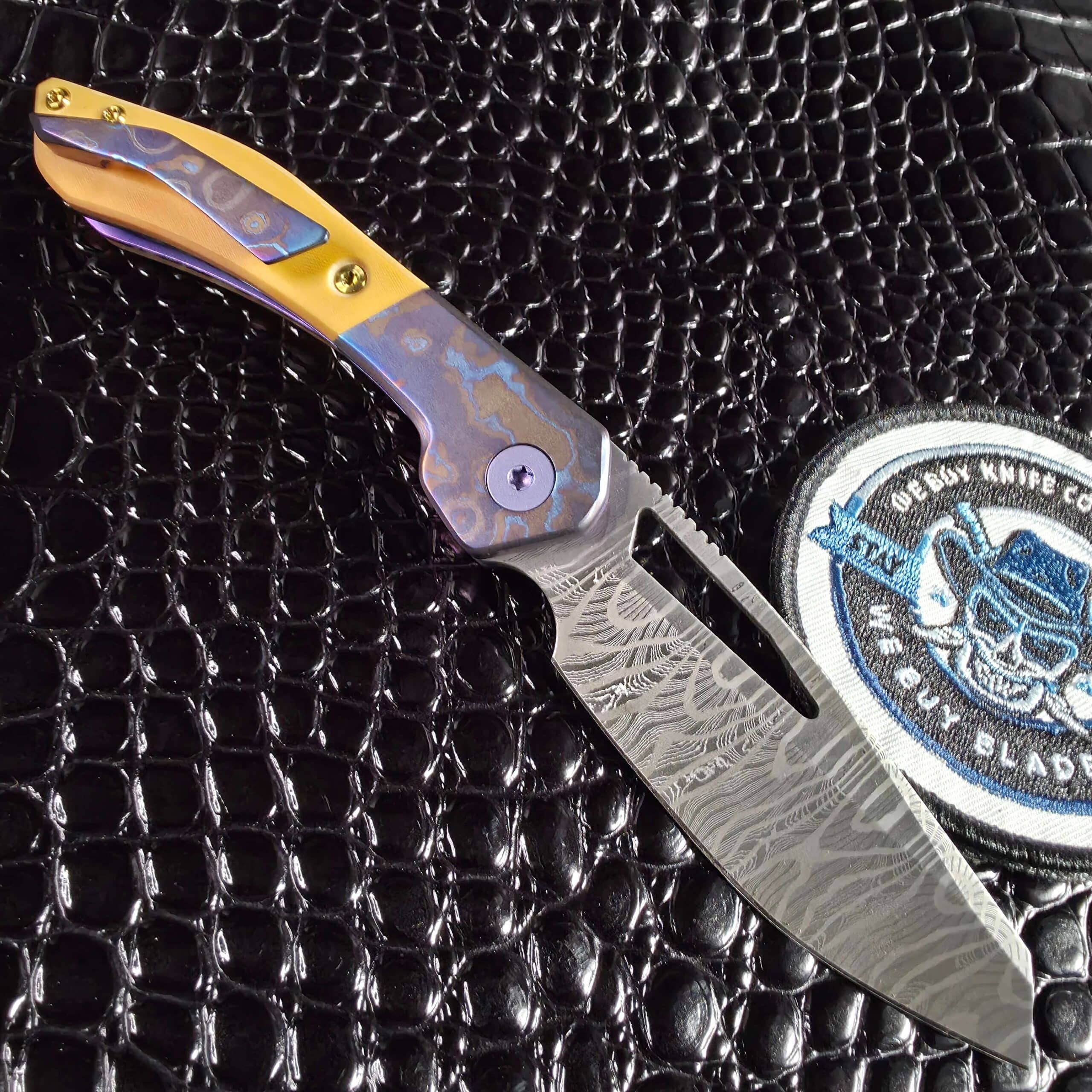 Keanison Bloodhound liner lock #15 open clip side beside the We Buy Knife Collections patch