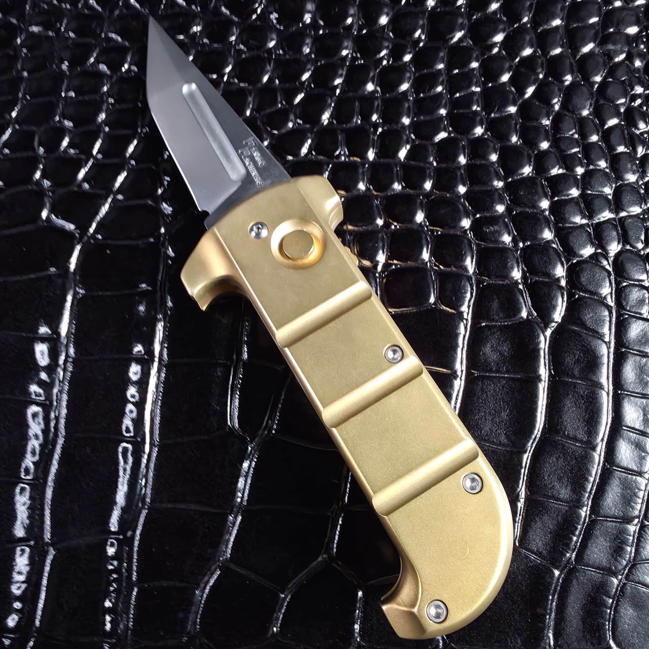 Angled view of the open Maniac Machining Stinger EDC brass automatic knife