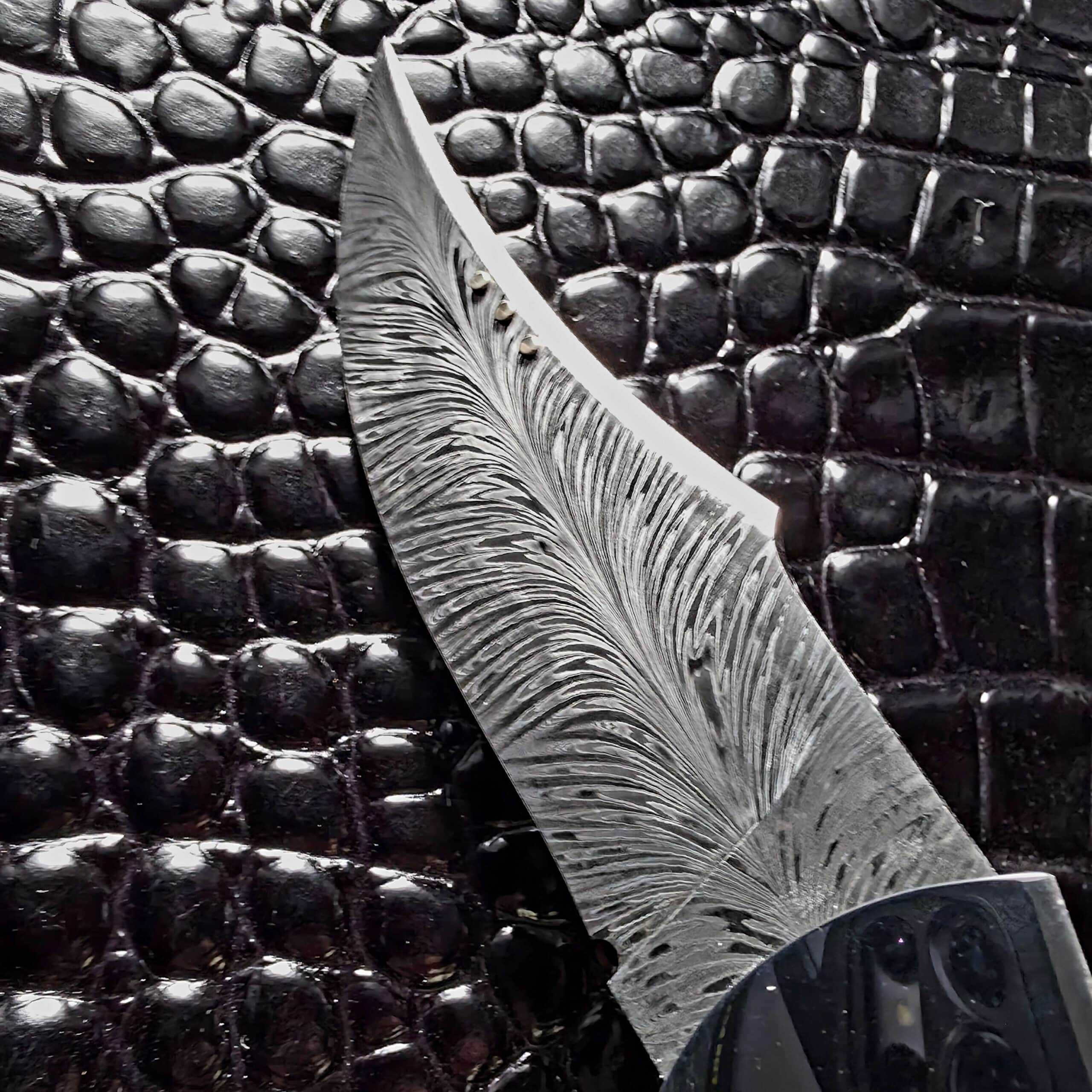 Feather damascus pattern running to the upswept tip of the Scott Gallagher Escalante folder blade
