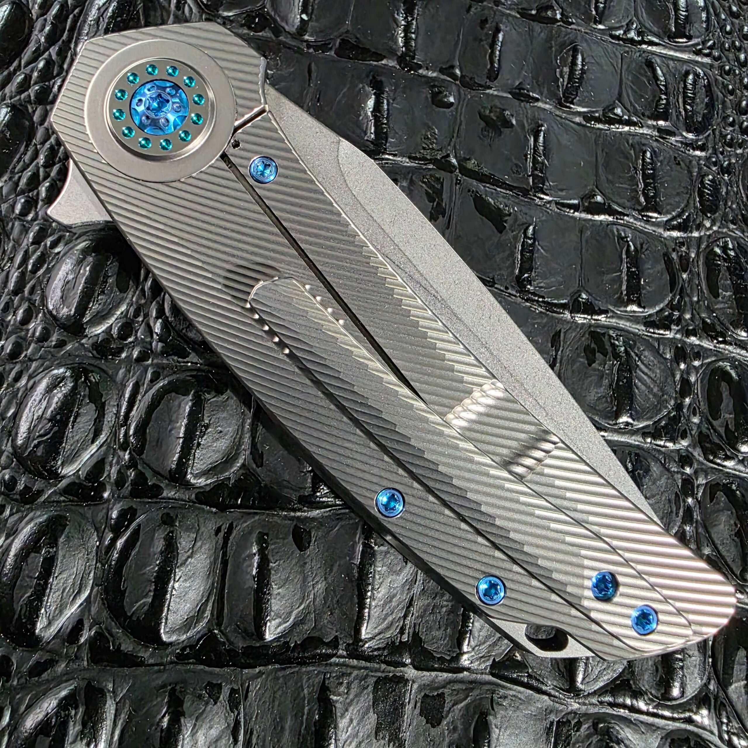 Closed clip side of the Skiff Made Blades Fugitive #0113 with the milled titanium pocket clip and blue anodized screws