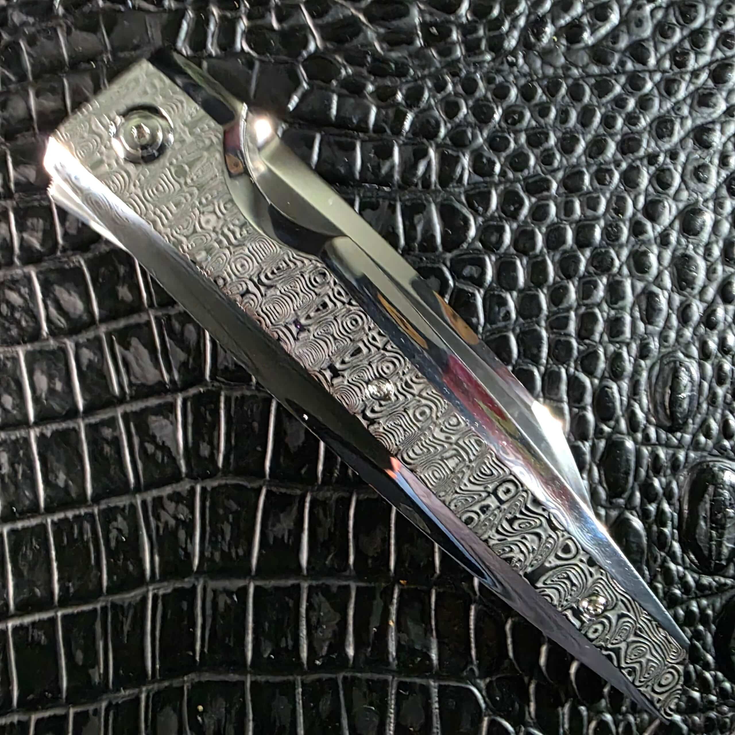 Closed Stefano Compostella StriaXL showing the full mirror-polished Damasteel Ladder handle scale and polished bolster