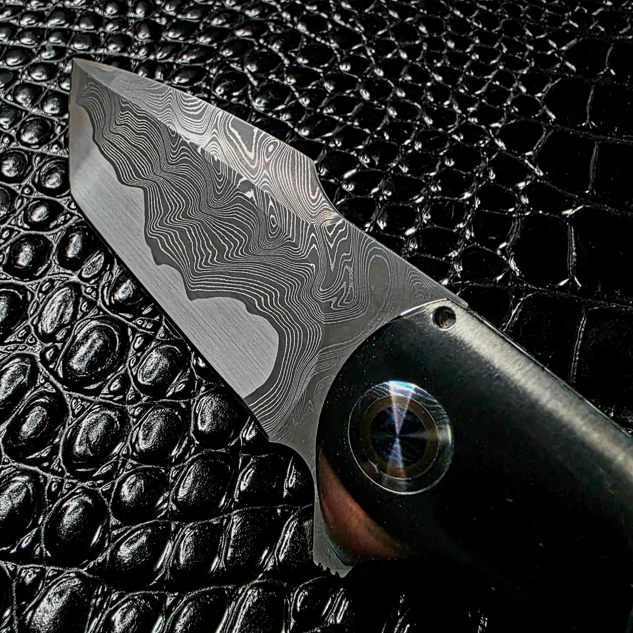 Damascus blade meeting the polished titanium bolster with mokuti pivot collar