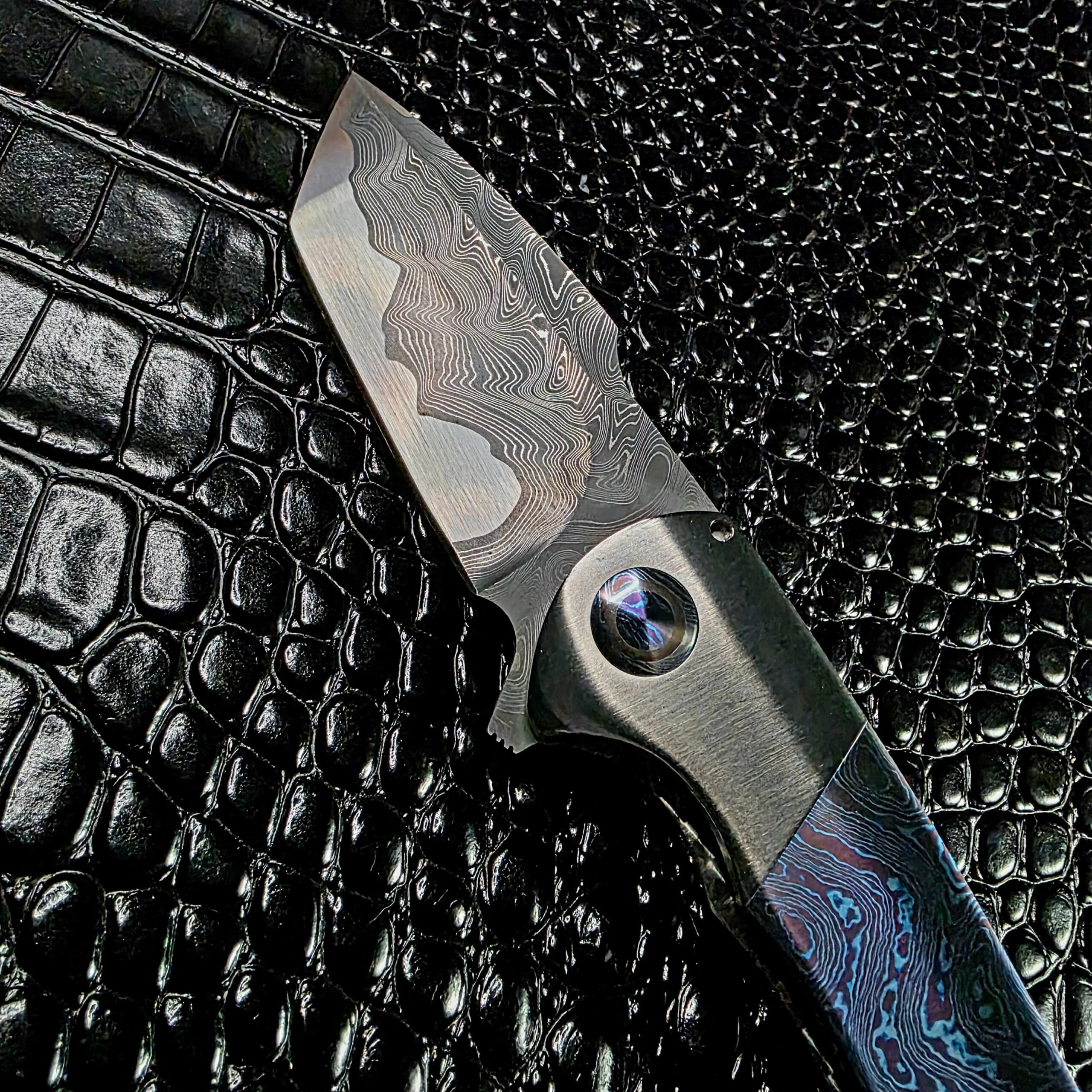 Todd Fischer Kamehameha open, showing the damascus blade profile and bolster