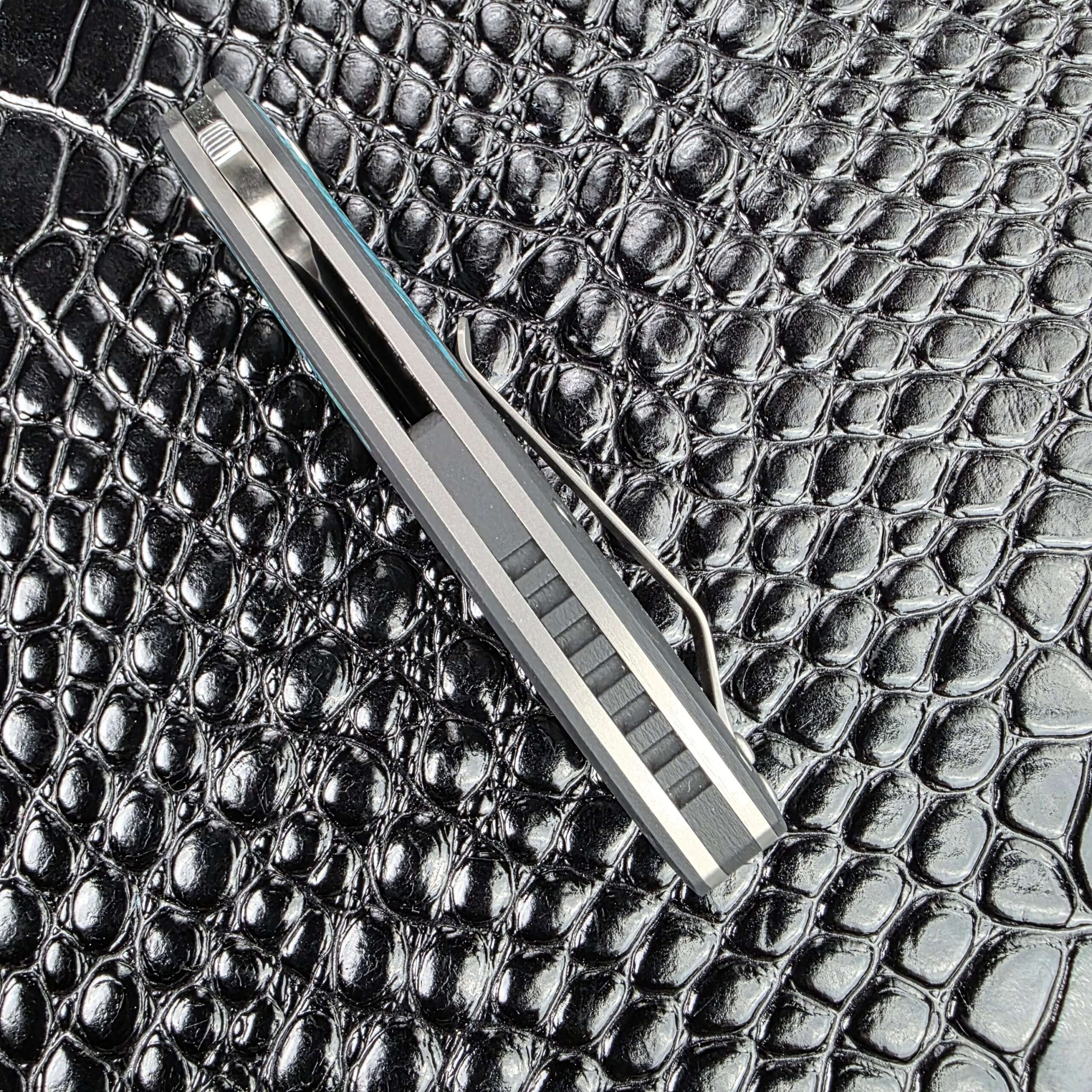 Spine of the closed 3LegDog M10 showing polished titanium liners and the G10 scales
