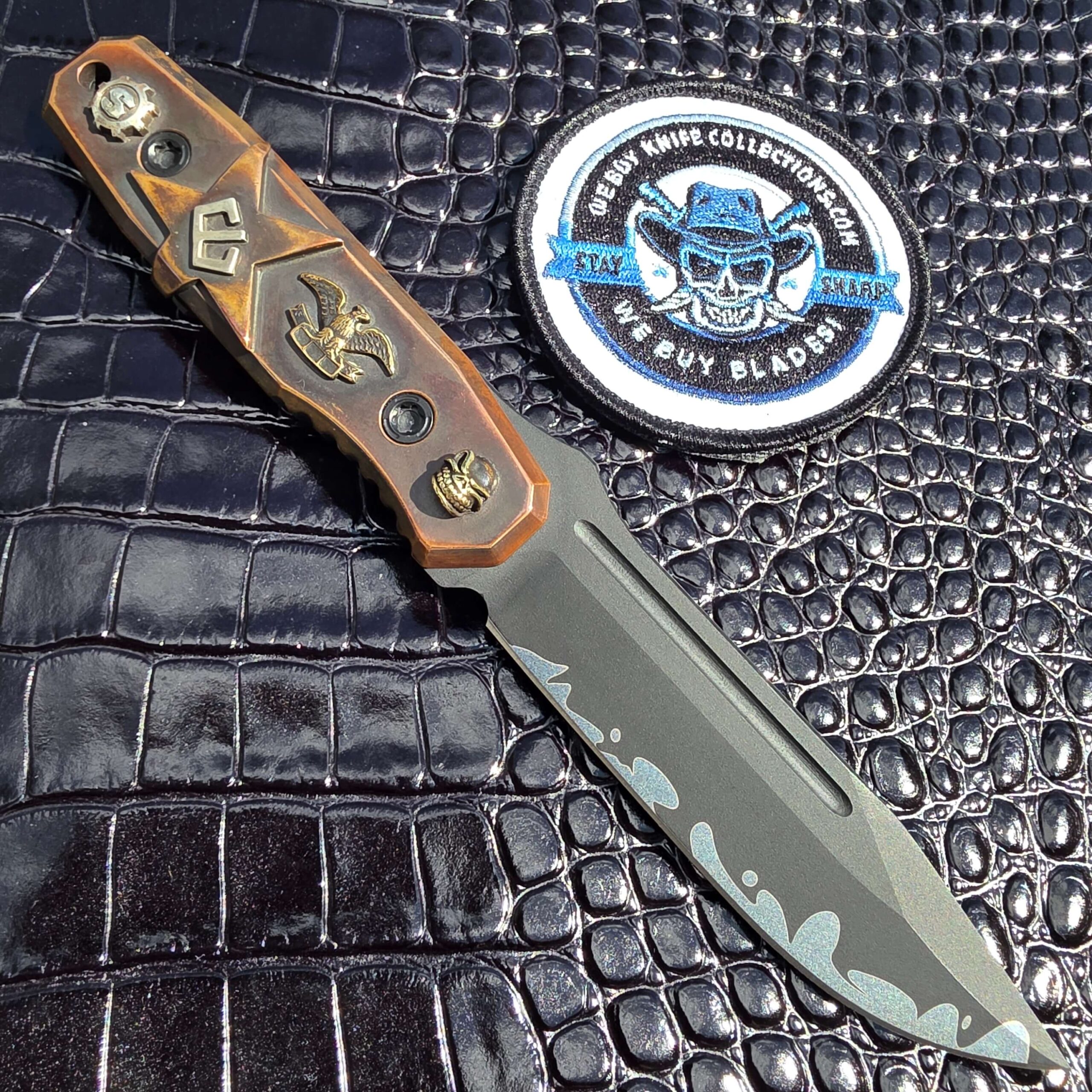 Blackside Customs Plan B on the reverse side showing the carved copper scale and cast elements, with the We Buy Knife Collections patch in frame