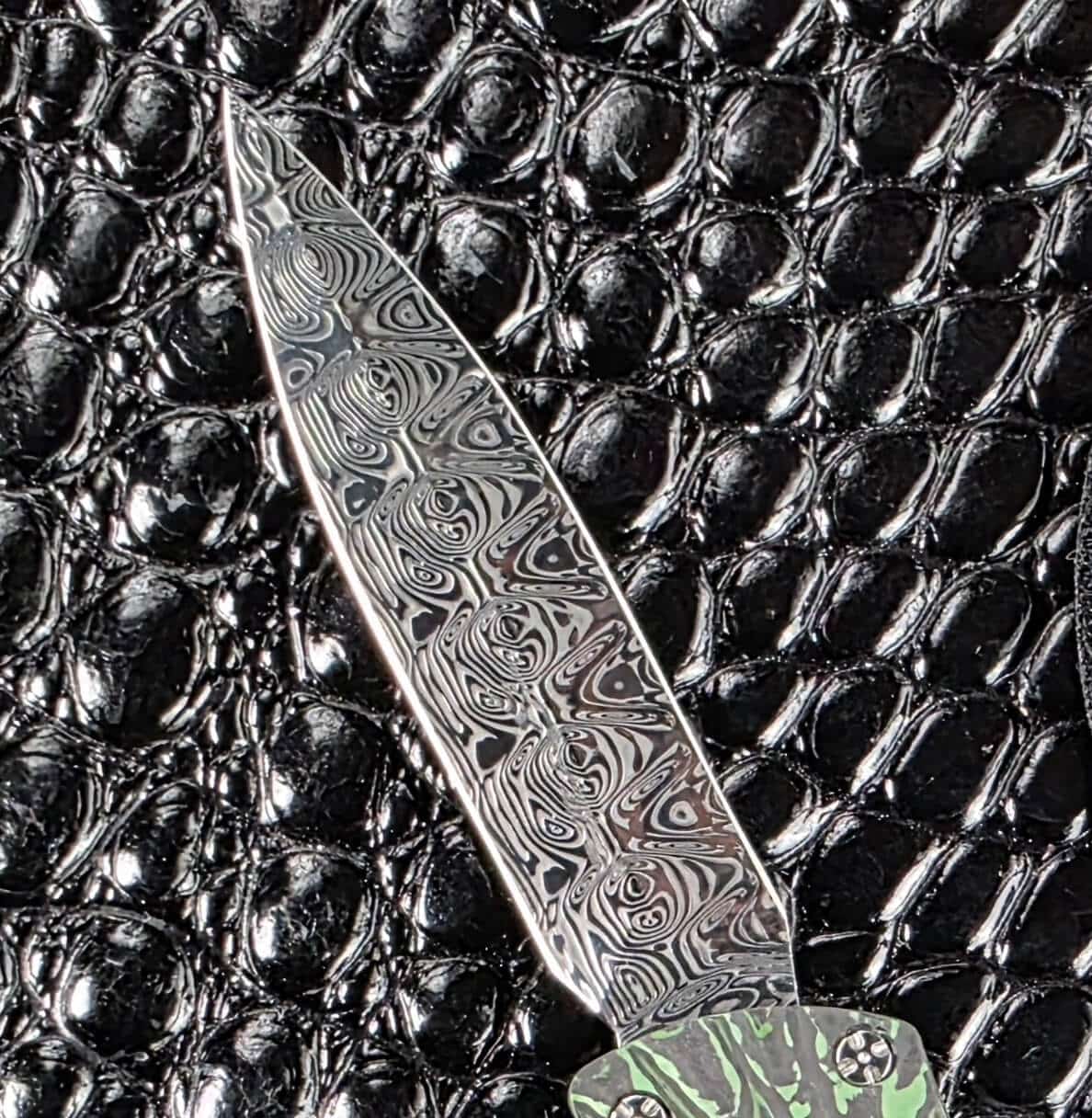 Damasteel dagger blade of the Brian Tighe Tighe Twist OTF, ground symmetrically to a centred point