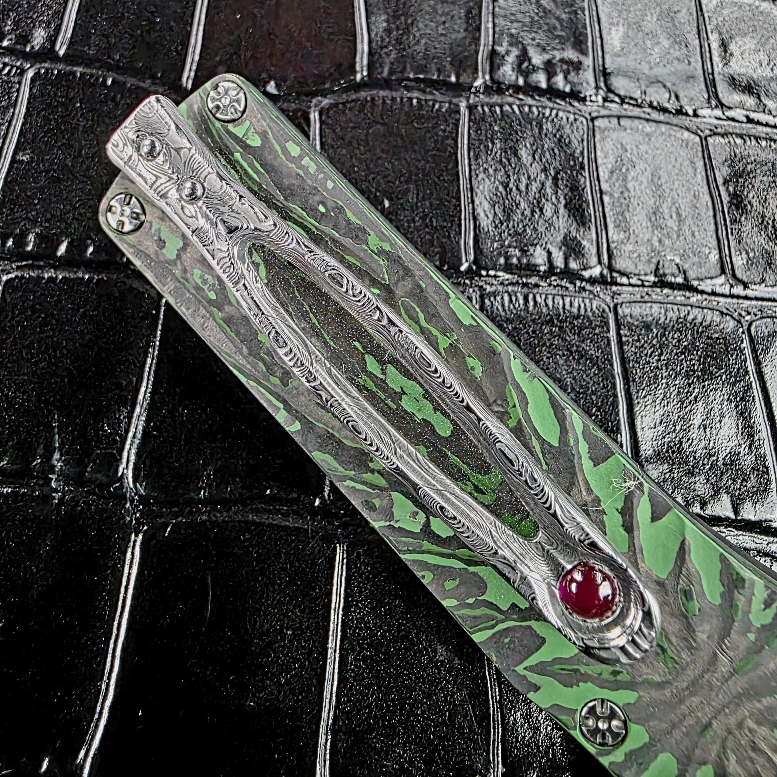 Damasteel pocket clip on the Brian Tighe Tighe Twist OTF with a ruby ball at the free end