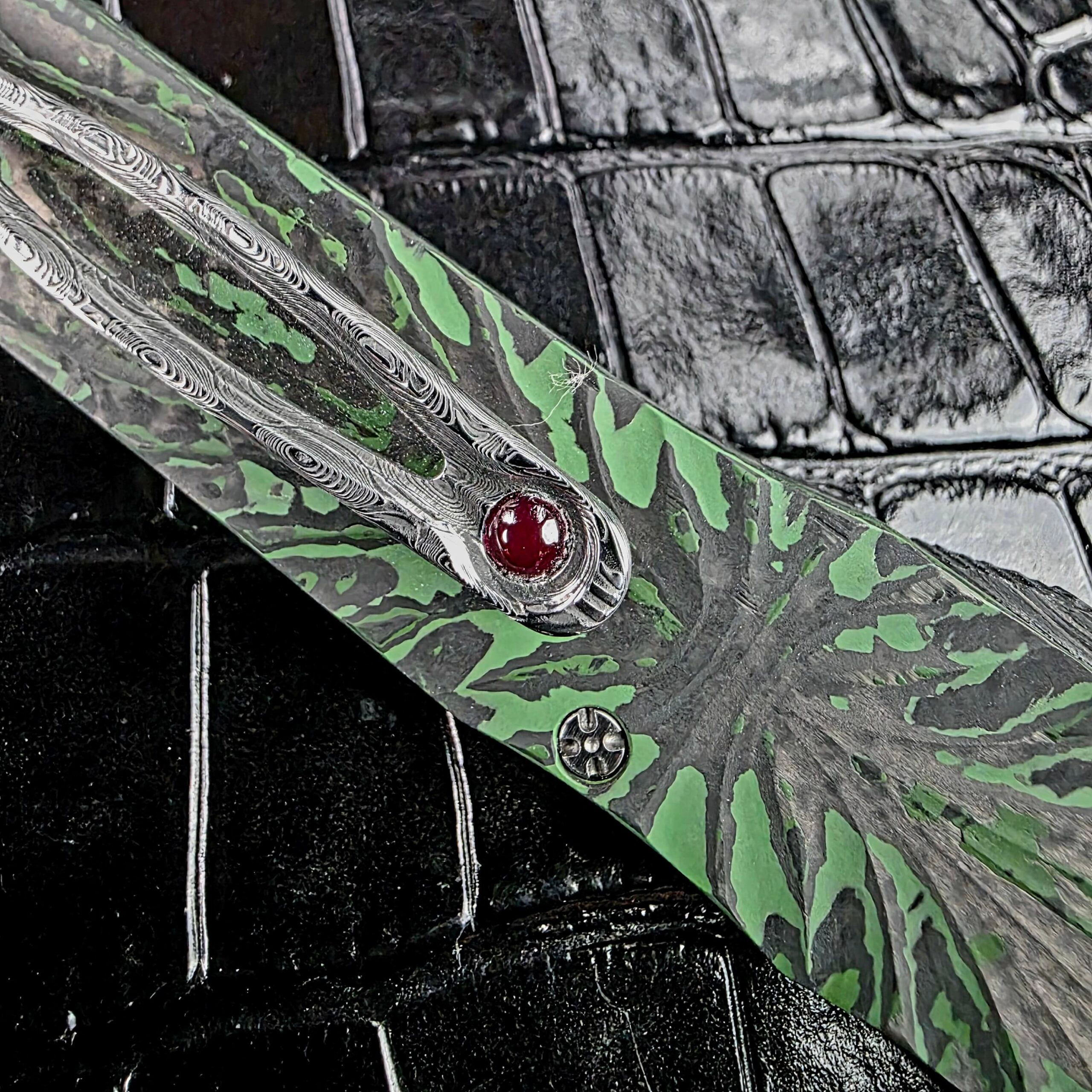 Ruby ball insert set into the Damasteel pocket clip of the Brian Tighe Tighe Twist OTF