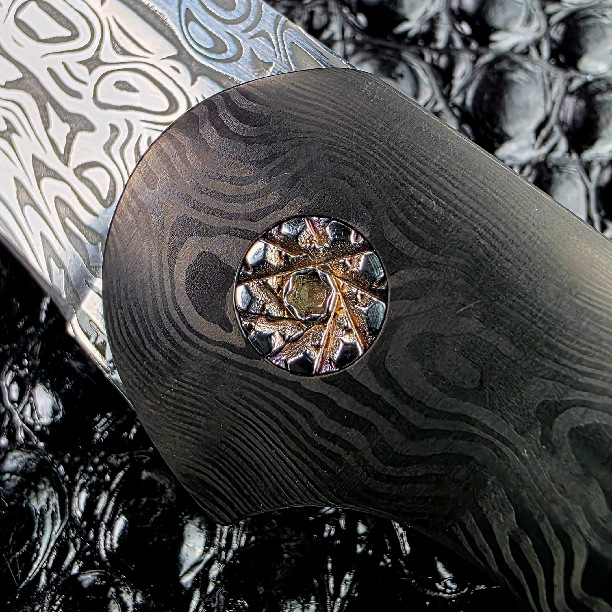 Macro of the faceted custom pivot by Glenn Are Hovin set into layered carbon fiber