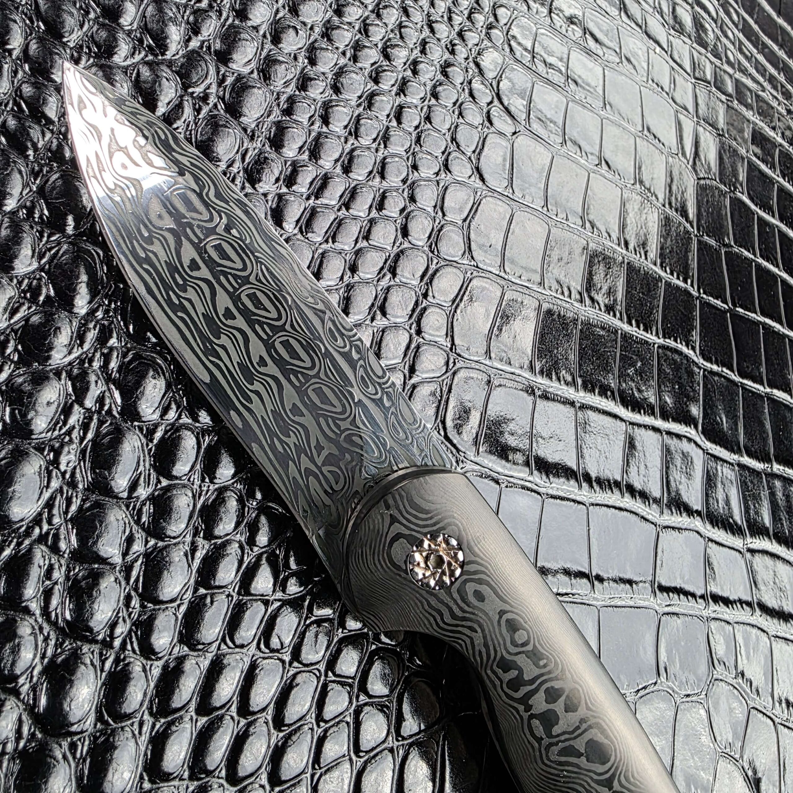 Damasteel Svavner blade of the Glenn Are Hovin Koda photographed at an angle with the faceted pivot in frame