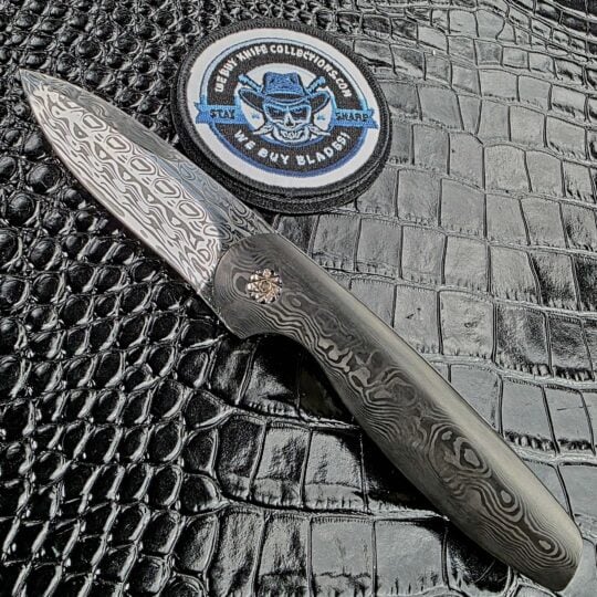 Glenn Are Hovin Koda front flipper shown open on the show side with the We Buy Knife Collections patch in frame