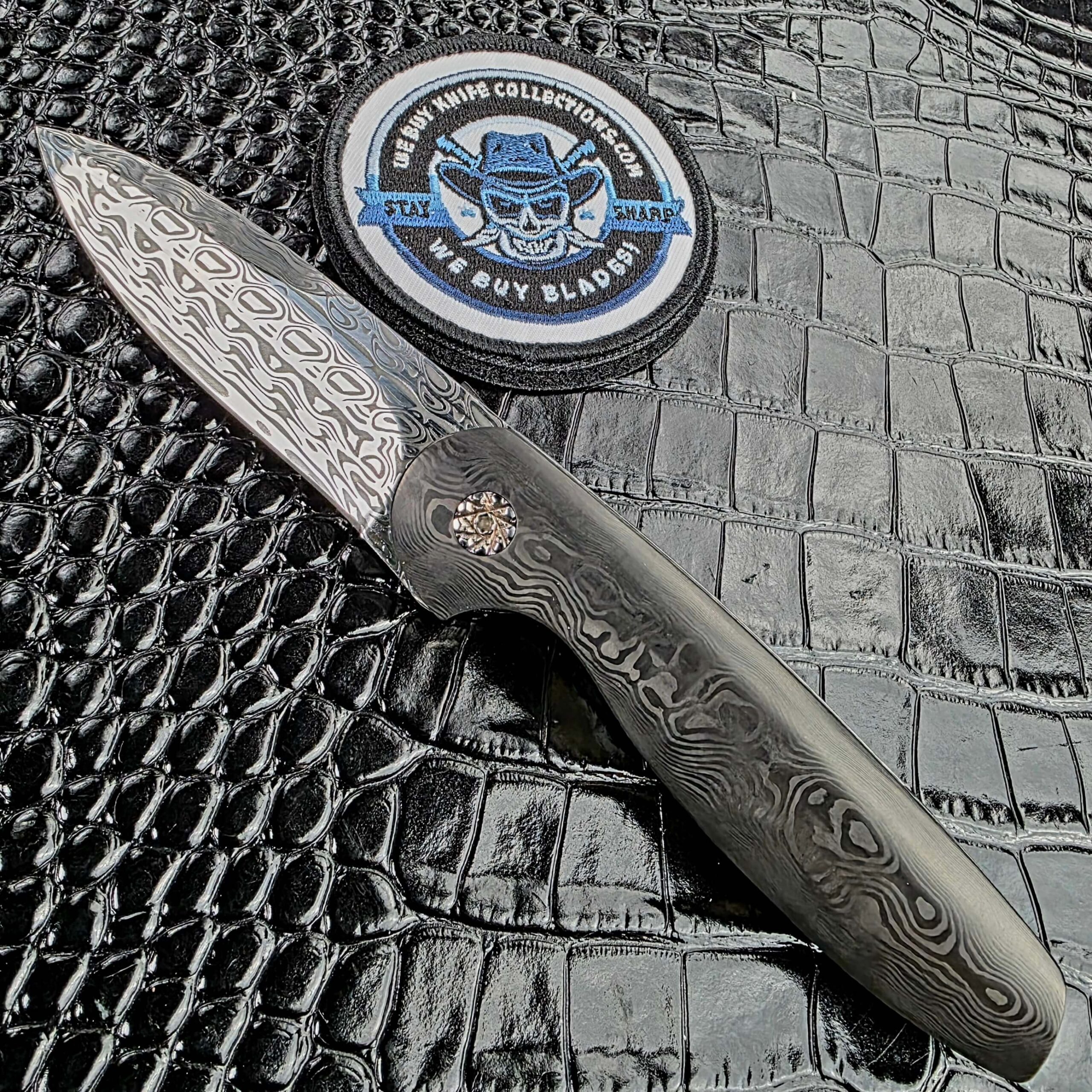 Glenn Are Hovin Koda front flipper shown open on the show side with the We Buy Knife Collections patch in frame