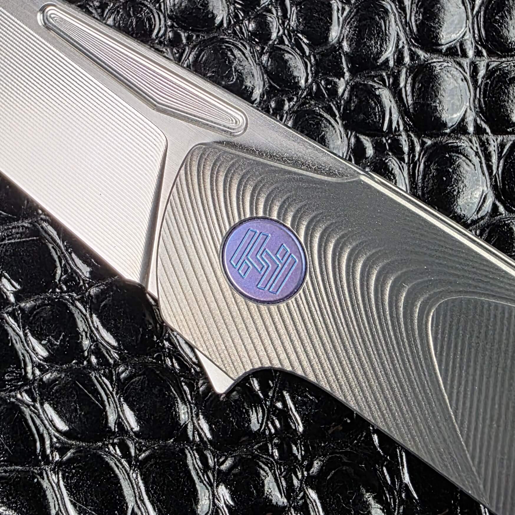 Blue Chameleon anodised pivot against the Gunmetal titanium frame of the Hog House Model T Gen 2