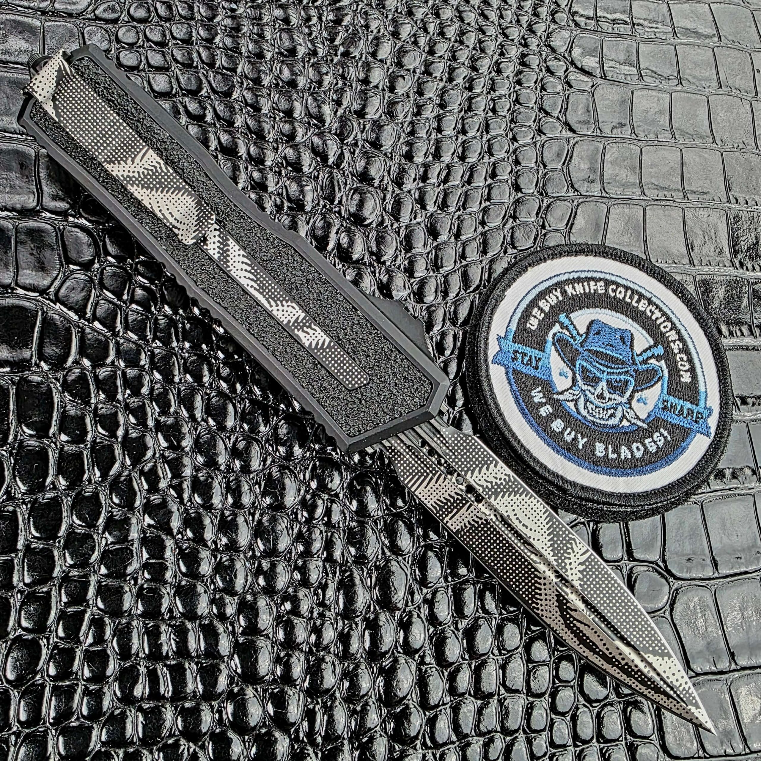 Microtech Scarab II Gen III deployed on the clip side showing the reversible steel pocket clip, with the We Buy Knife Collections patch in frame