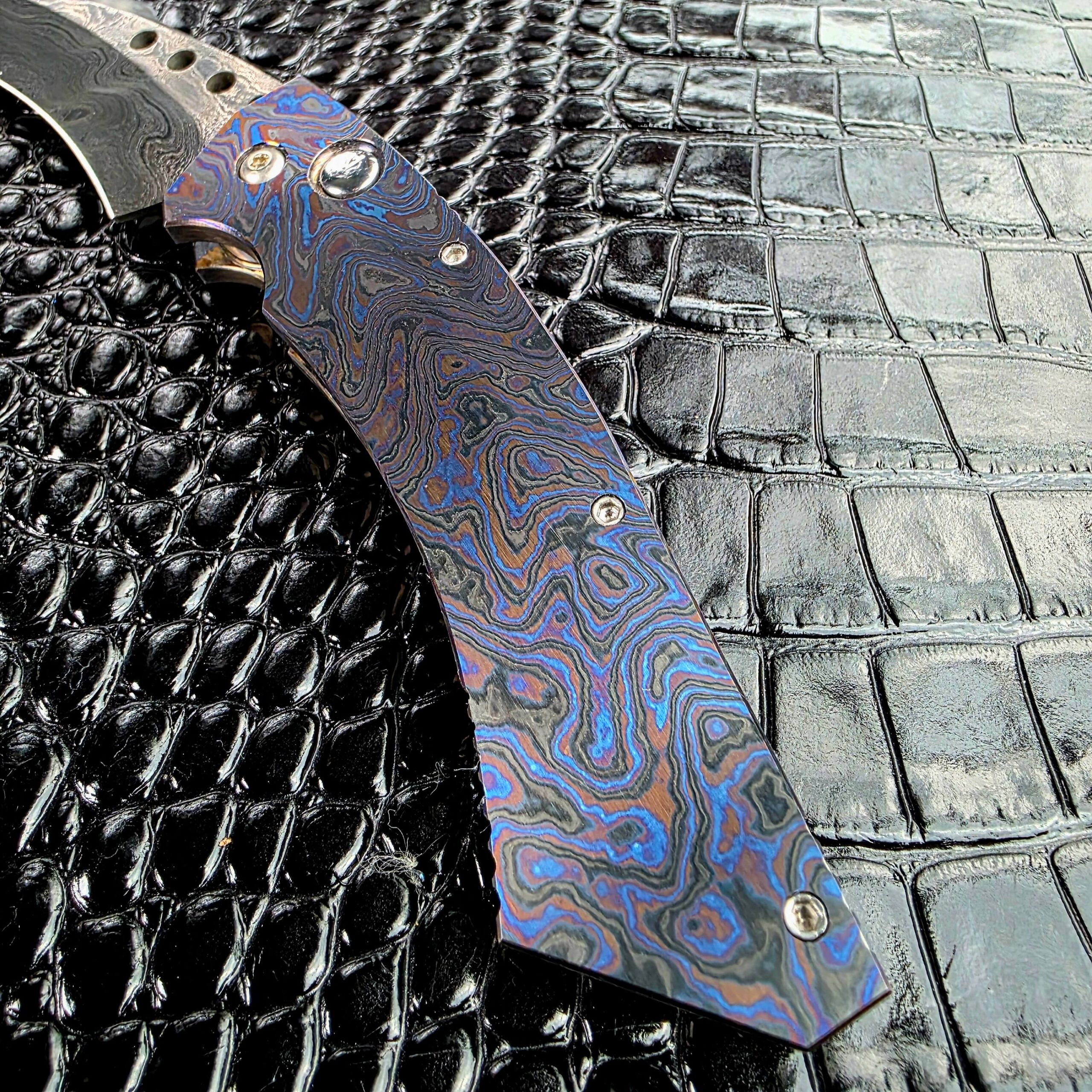 Recessed plunge lock button set into the Timascus frame of the Reese Weiland Hawkbill 2nd Gen