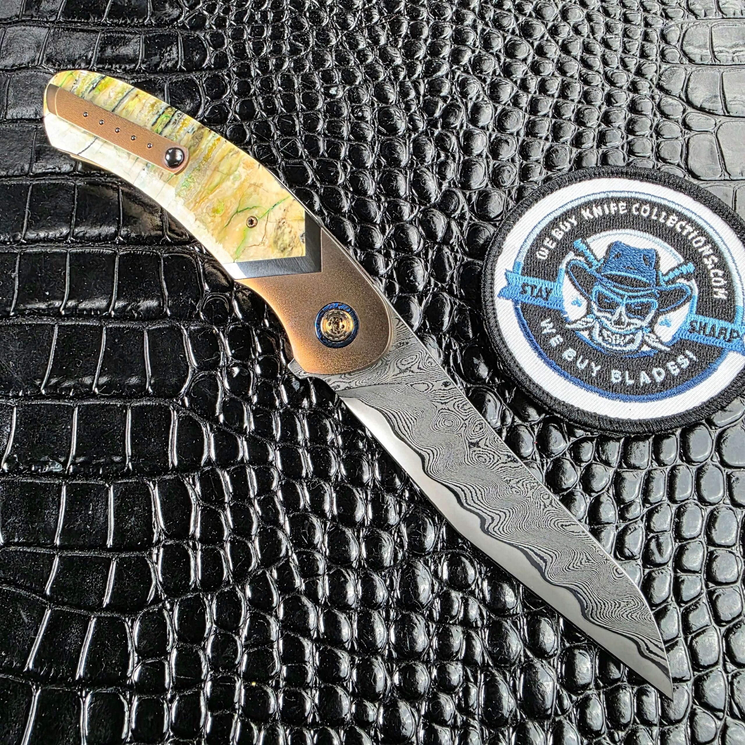 Andriy Mozil Model 22-26 Custom open on the clip side showing the fitted pocket clip, with the We Buy Knife Collections patch in frame