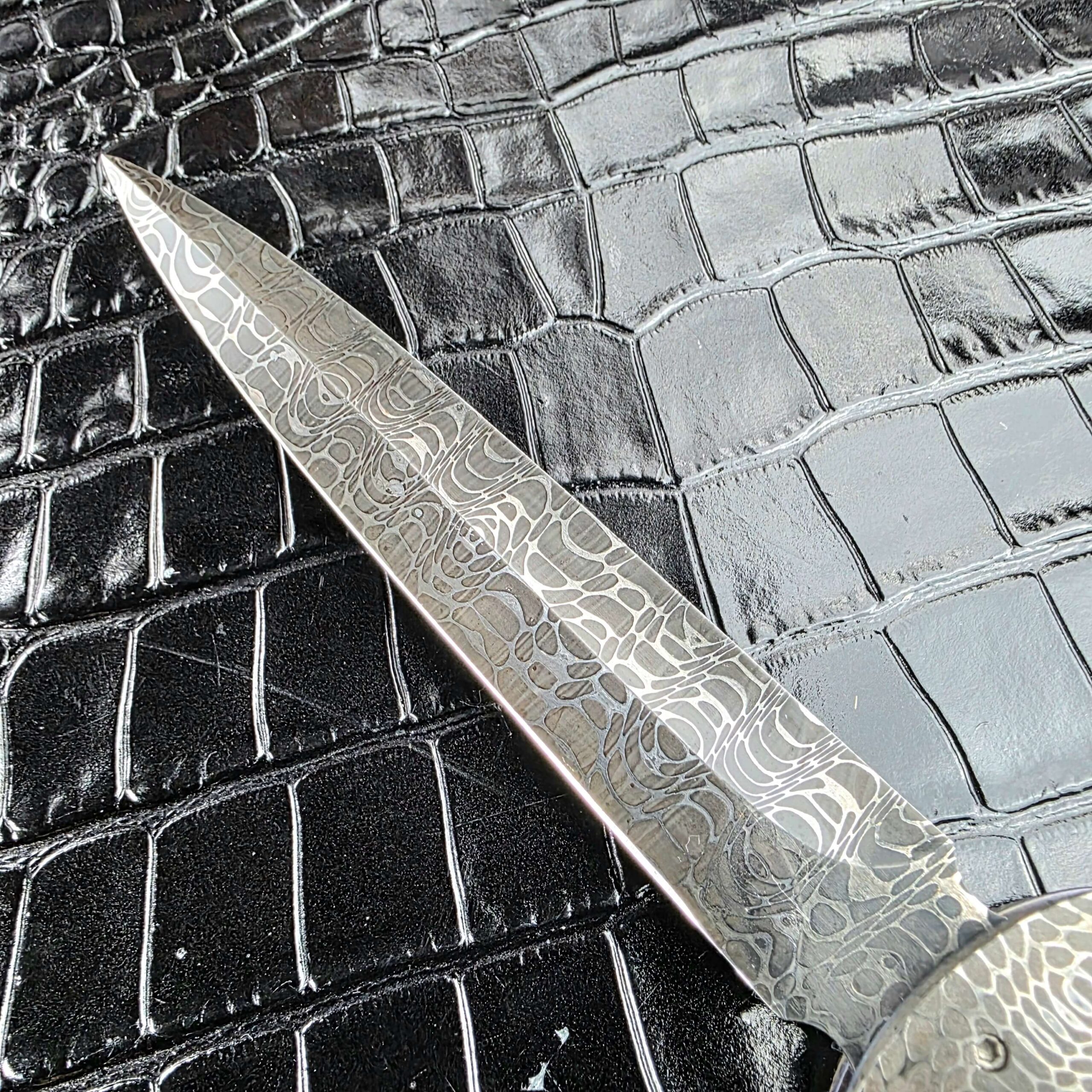 Tip of the Chad Nichols Damascus dagger blade on the Burn Knives Automatic Dagger