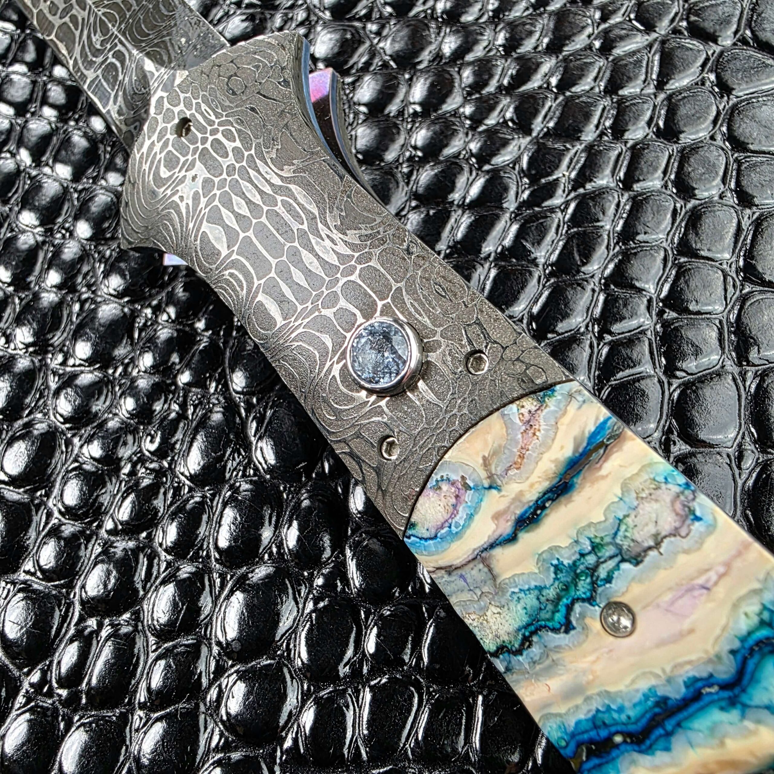 Firing button set into the Chad Nichols Damascus bolster beside the mammoth molar scale
